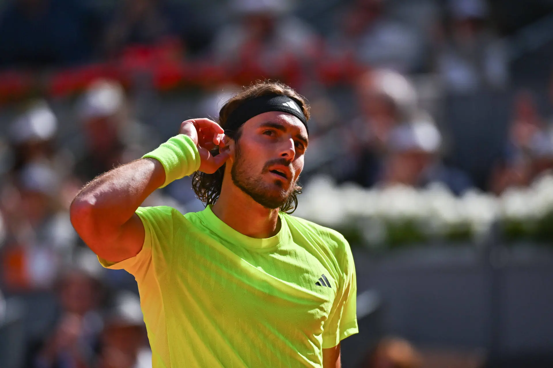 Stefanos Tsitsipas touches his ear and encourages the crowd.