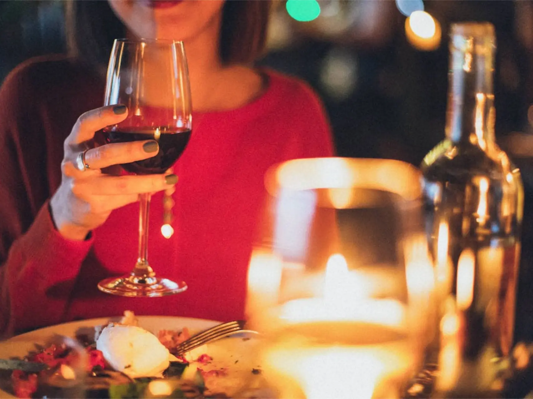 een vrouw met een glas wijn aan tafel