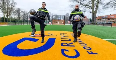 de twee agenten houden een bal hoog op het cruyff court in rozenburg