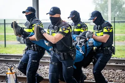 de politie heeft demonstranten van het spoor afgetild