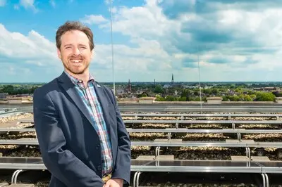 ar20240619 0030 gouda wethouder michel klijmij van der laan tussen de zonnepanelen op het dak van het huis van de stad
