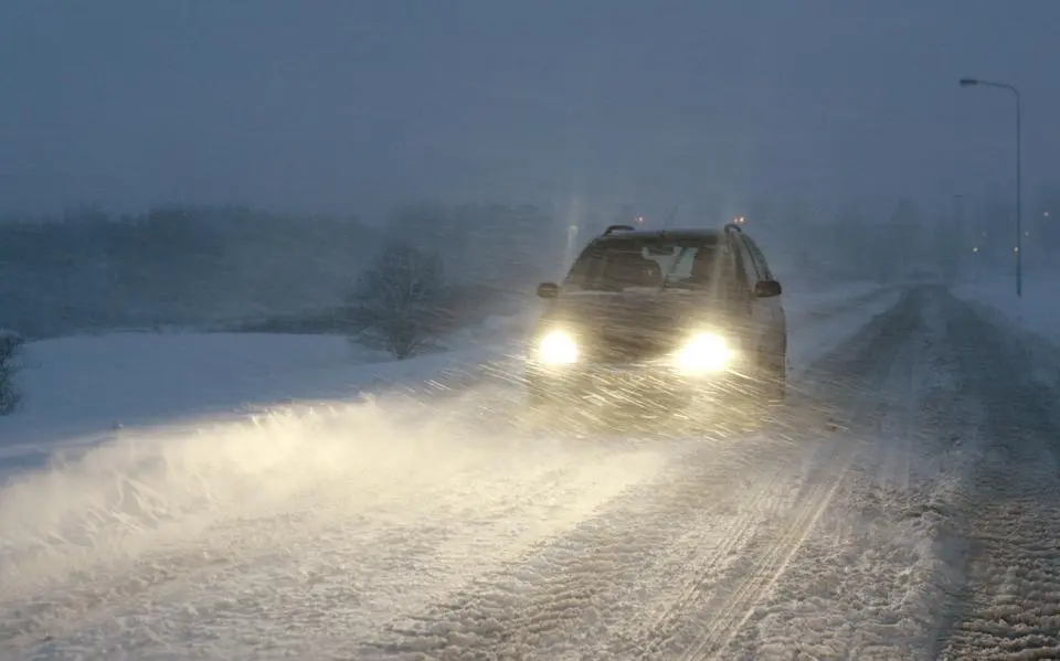 een20auto20rijdt20door20stuivende20sneeuw20terwijl20harde20wind20het20zicht20op20de20weg20sterk20beperkt