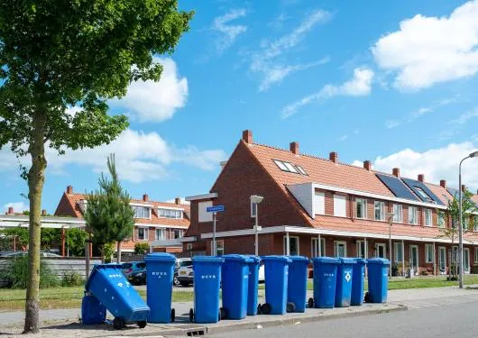 rij blauwe papiercontainers langs de weg