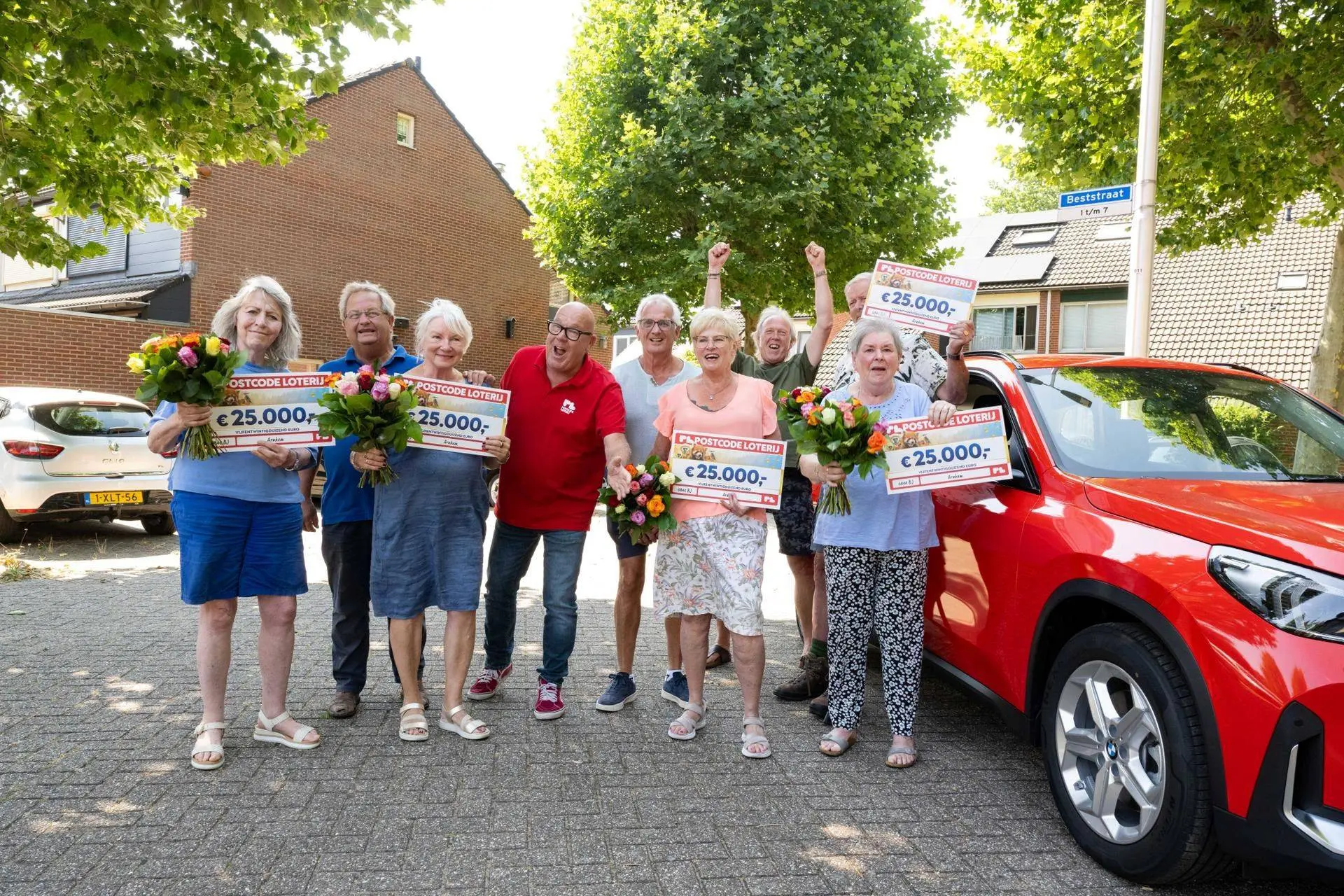 Postcode Loterij-ambassadeur Gaston Starreveld verrast de gelukkige winnaars uit Arnhem met de cheques.