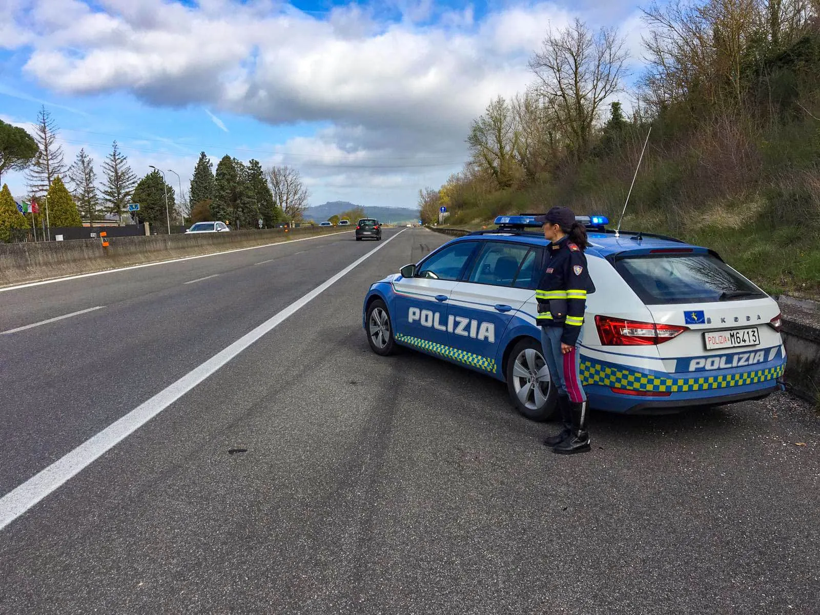 controlli polizia strdale, pattuglia a bordo strada che ferma le vettura con un poliziotto affianco all'auto