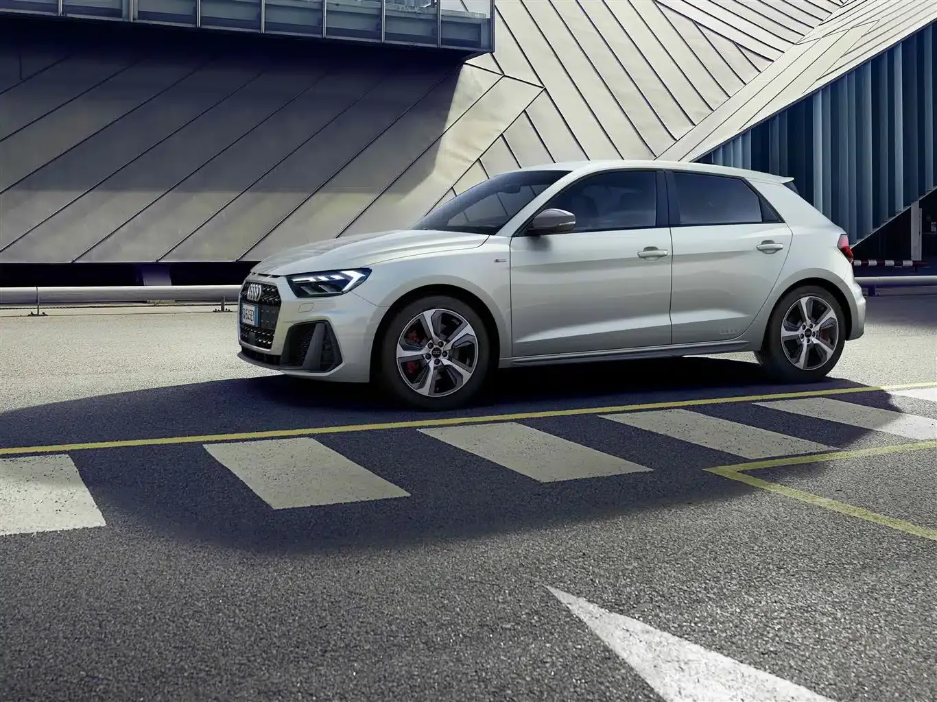 audi a1 sportback di colore bianco di lato su una strada con sfondo un palazzo moderno