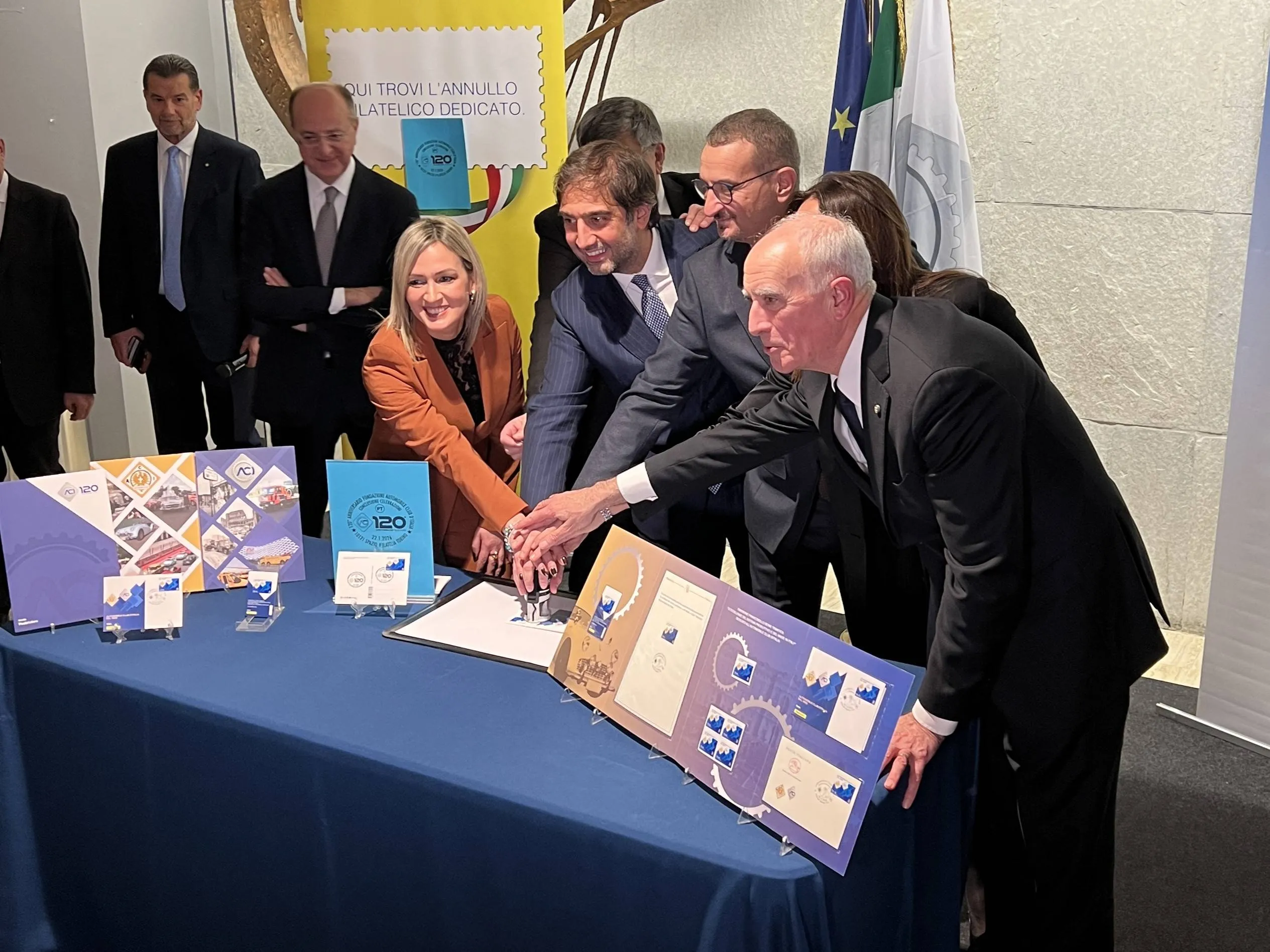 Cerimonia per i 120 anni ACI: autorità e dirigenti effettuano simbolicamente l'annullo del francobollo celebrativo su un tavolo allestito con i prodotti filatelici dell'evento. Presente il presidente ACI Geronimo La Russa