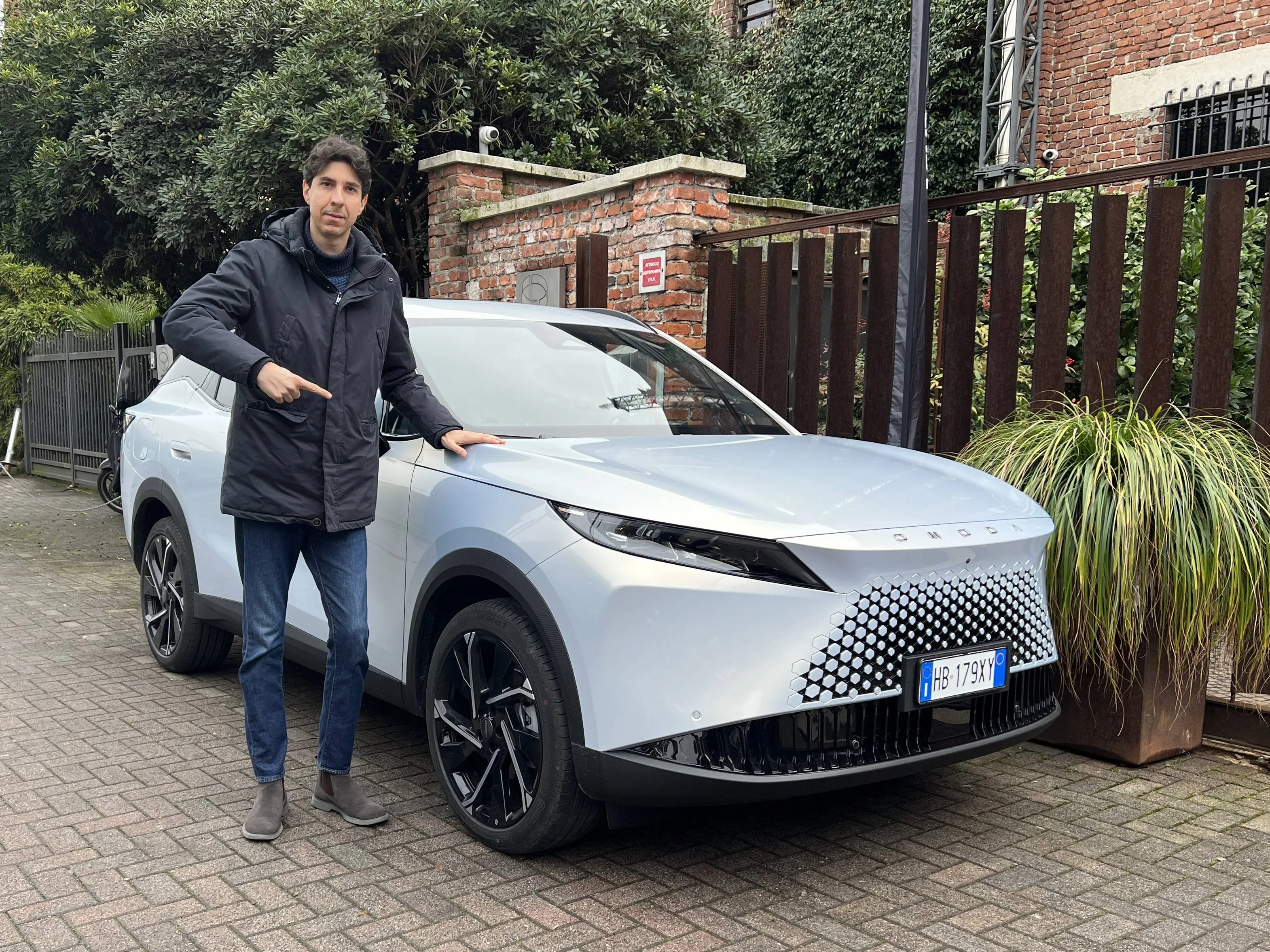 Omoda 7 SHS-P plug-in super ibrida vista frontalmente con una persona accanto