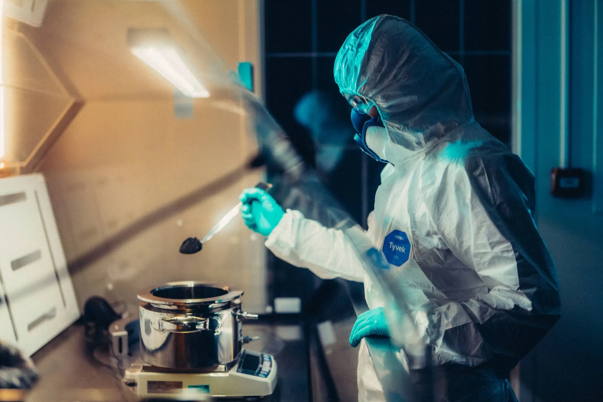 persona in camice coperto fino al volto che lavora in un laboratorio