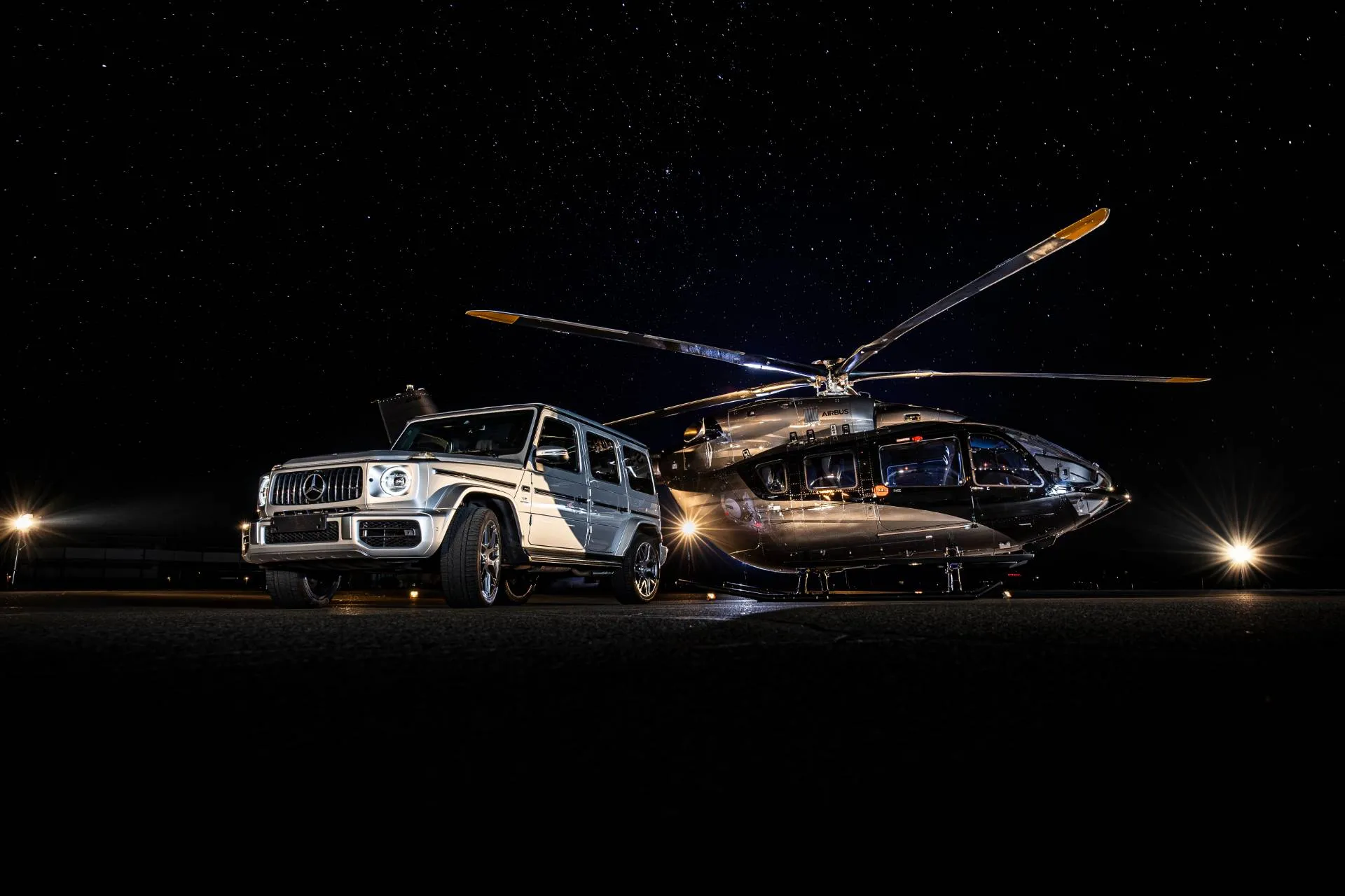 Elicottero di Airbus con Mercedes Benz Classe G al suo fianco di colore grigio