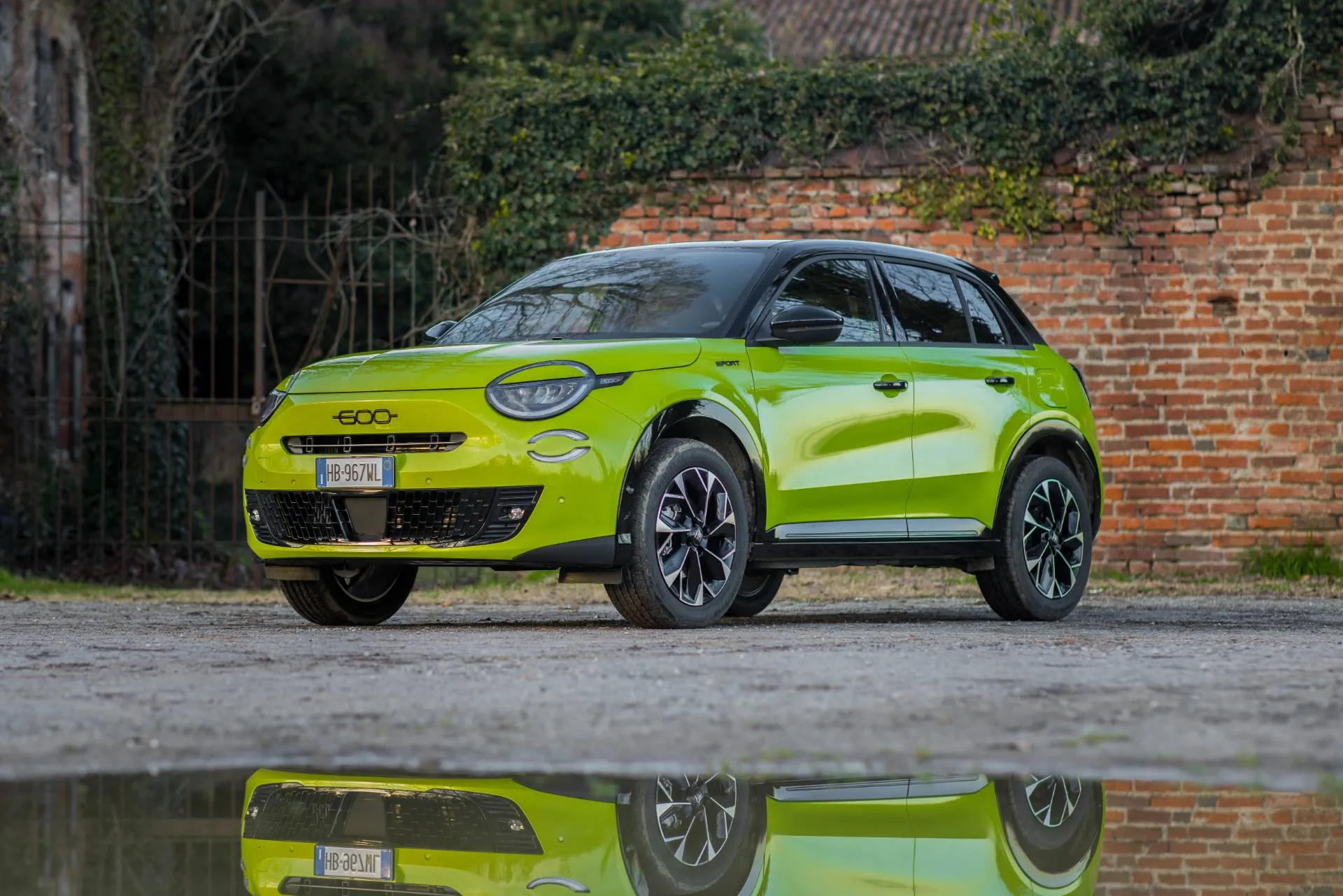 fiat 600 sport milano cortina di colore giallo fluo di muso davanti a una pozza d'acqua