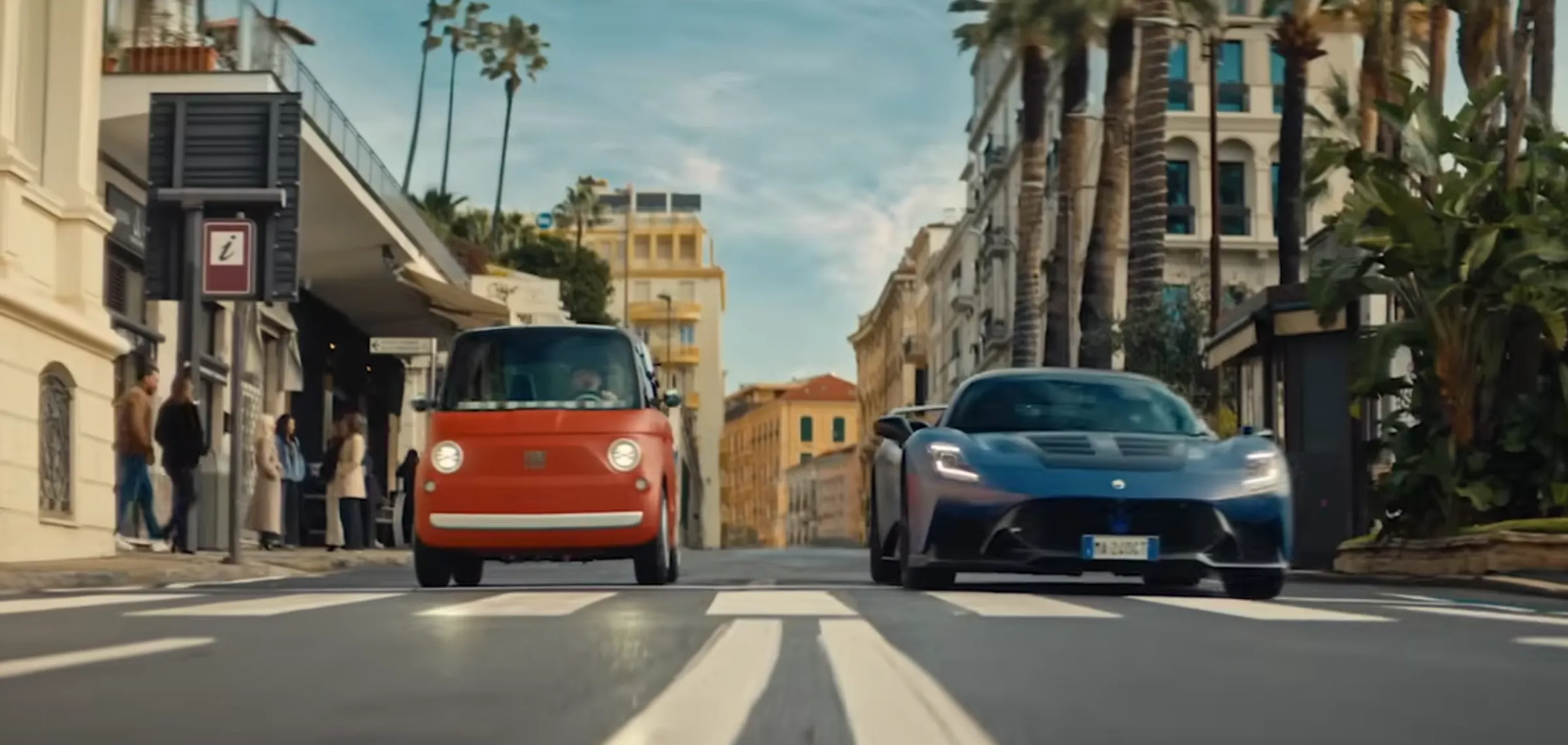 Vista frontale della Fiat Topolino color Corallo e della supercar Maserati GT2 Stradale blu mentre viaggiano affiancate sulle strade di Sanremo nello spot "Non c'è gara".