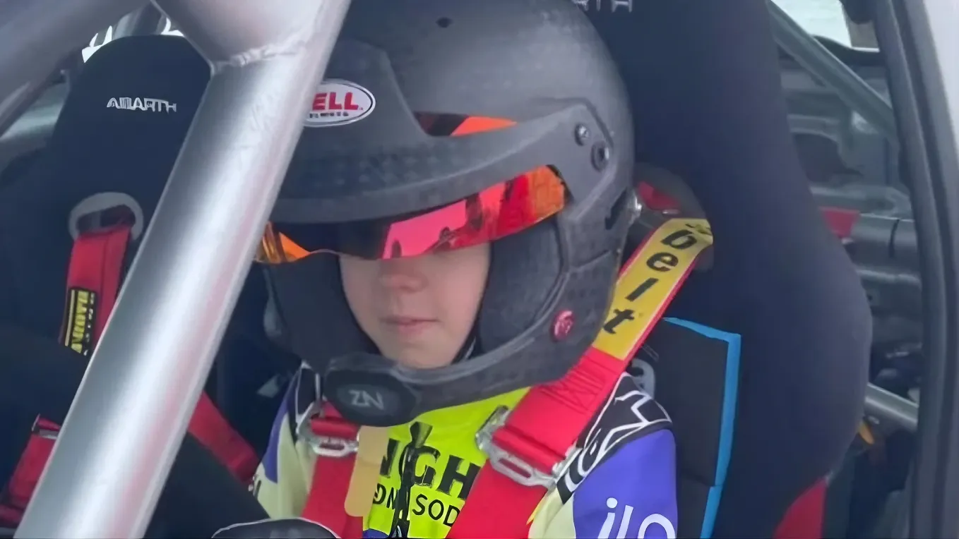 Figlio raikkonen che guida un'auto da rally, seduto con il casco e la cintura a quattro punti
