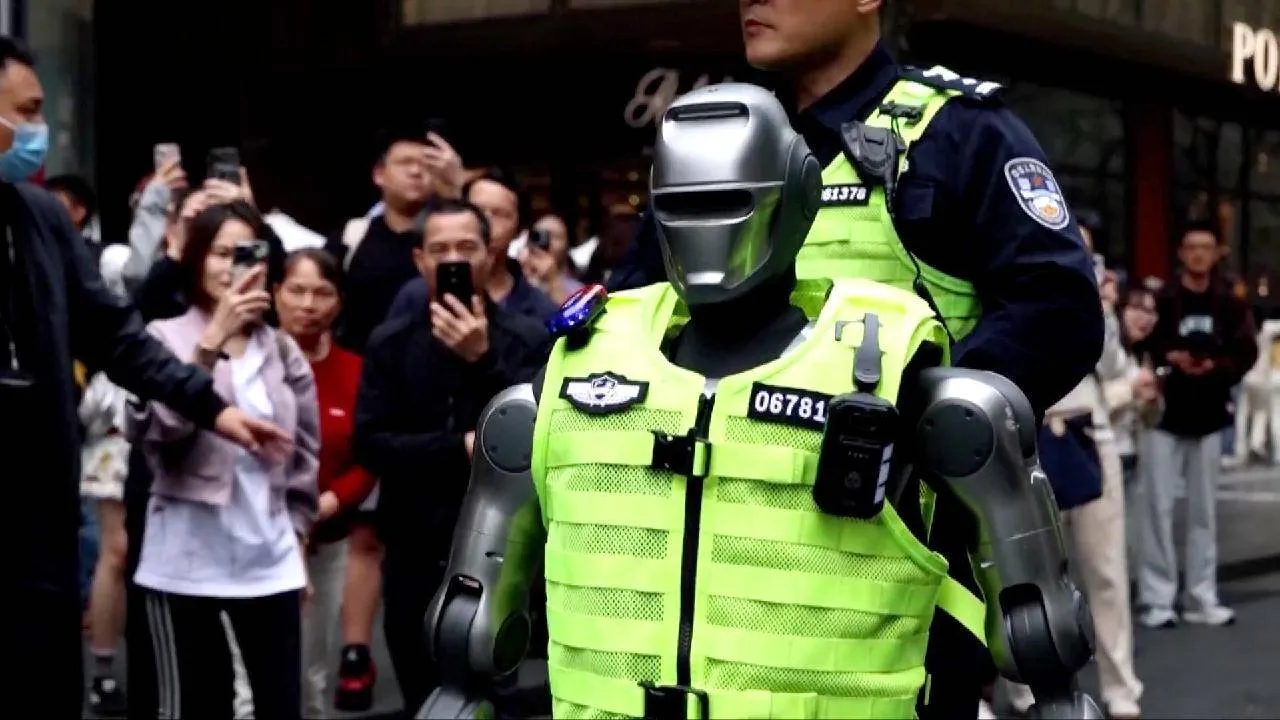 La foto ritrae il nuovo poliziotto robotico cinese mentre è per strada, controllato strettamente da un collega umano. Nello sfondo si vedono curiosi che registrano video e fanno foto