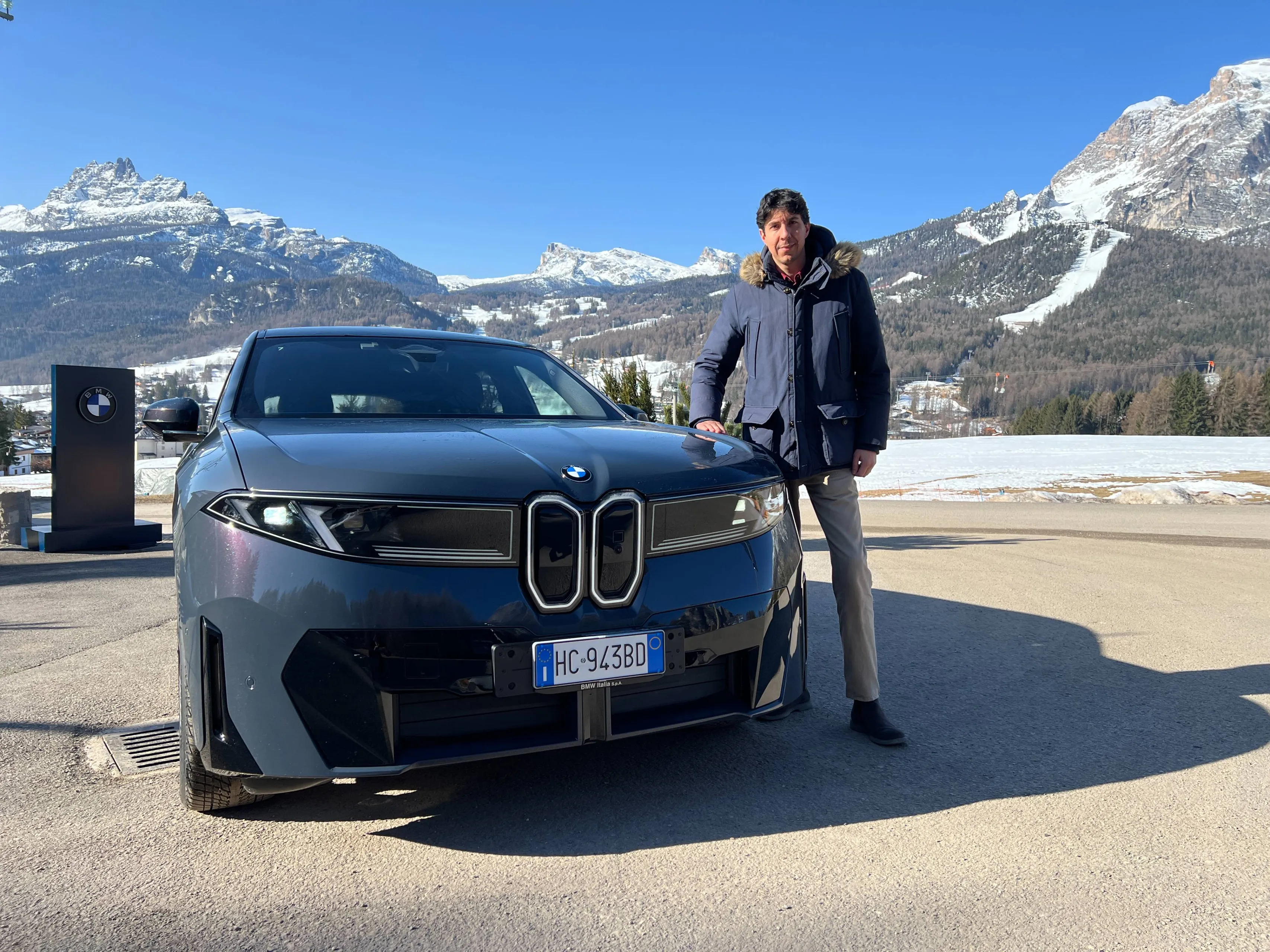 Federico Ferrero al fianco della bmw ix3 di colore blu grigio con sfondo montagne