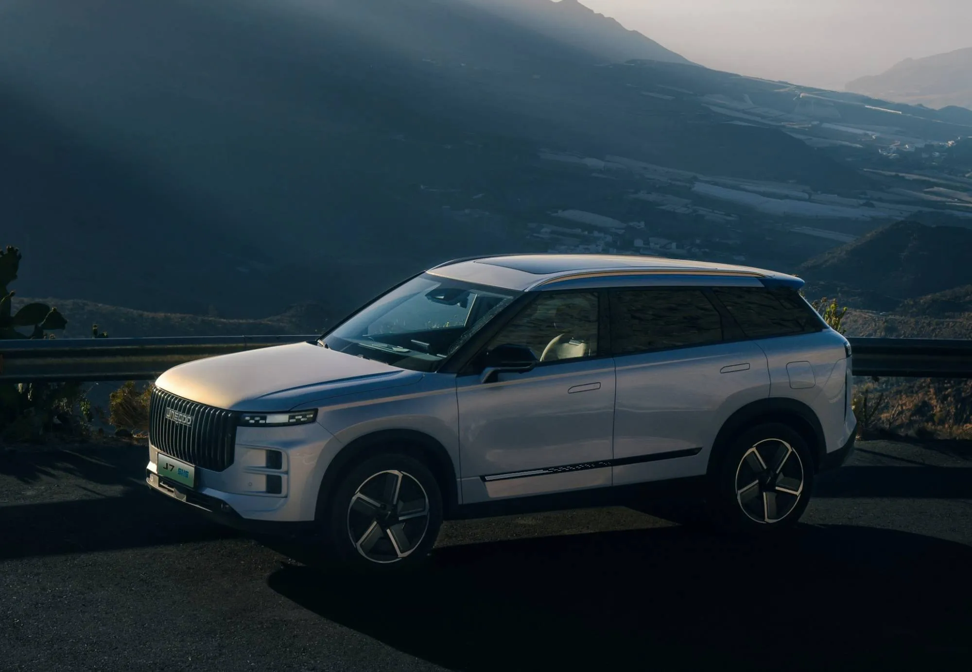 jaecoo 7 di colore grigio parcheggiata di lato con sfondo montagne