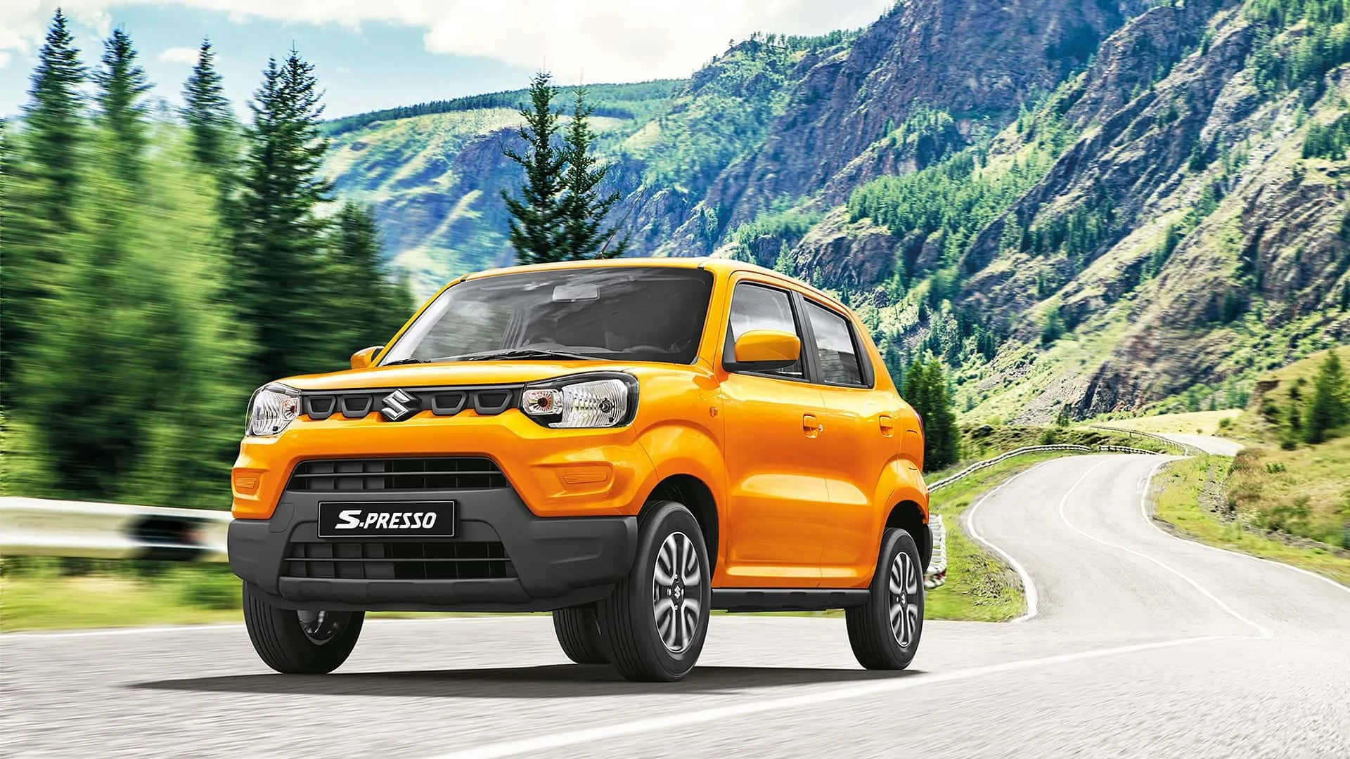Suzuki S-Presso 2026 di colore arancione che percorre una strada tra le montagne