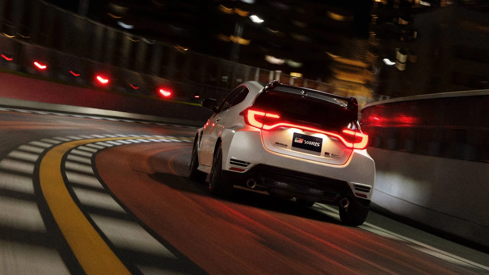 Toyota-Yaris-GR in curva di colore bianco con i fari posteriori accesi in curva su strada