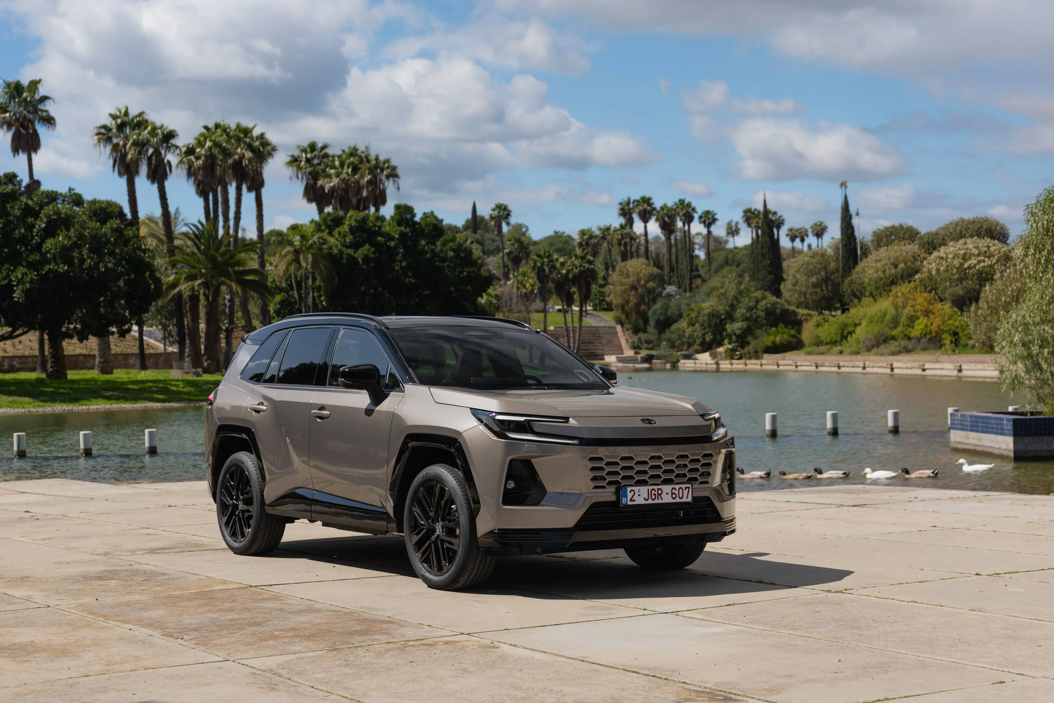 Toyota Rav4 ibrido di colore beige con sfondo di un laghetto in posizione anteriore