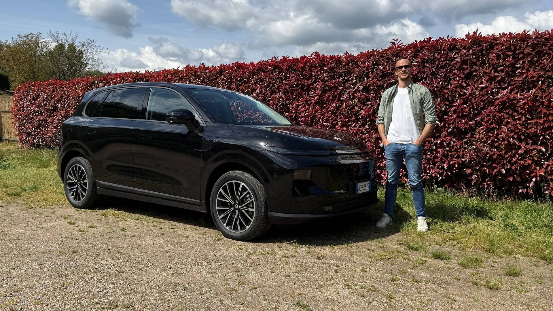 La Leapmotor B10 REEV di colore nero metalizzato con dietro una siepe rossa