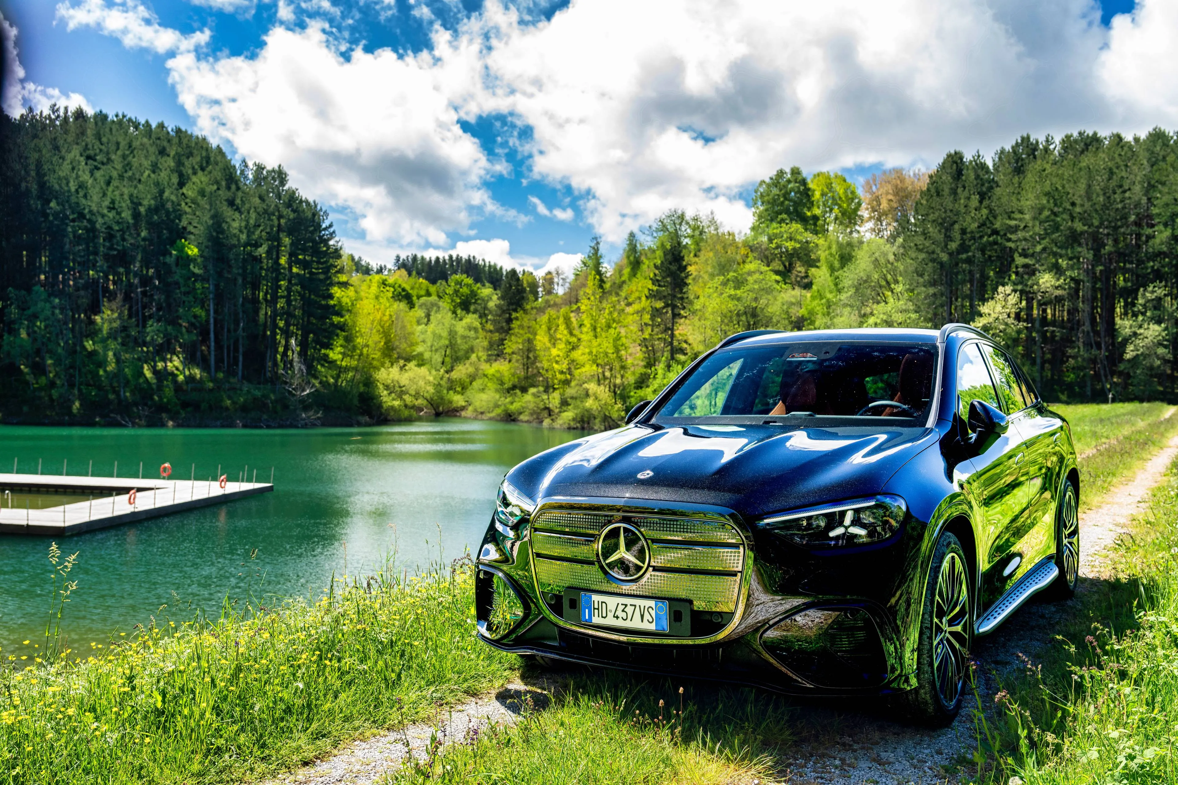 SUV Mercedes-Benz GLC EQ nero lungo lago con natura toscana sullo sfondo