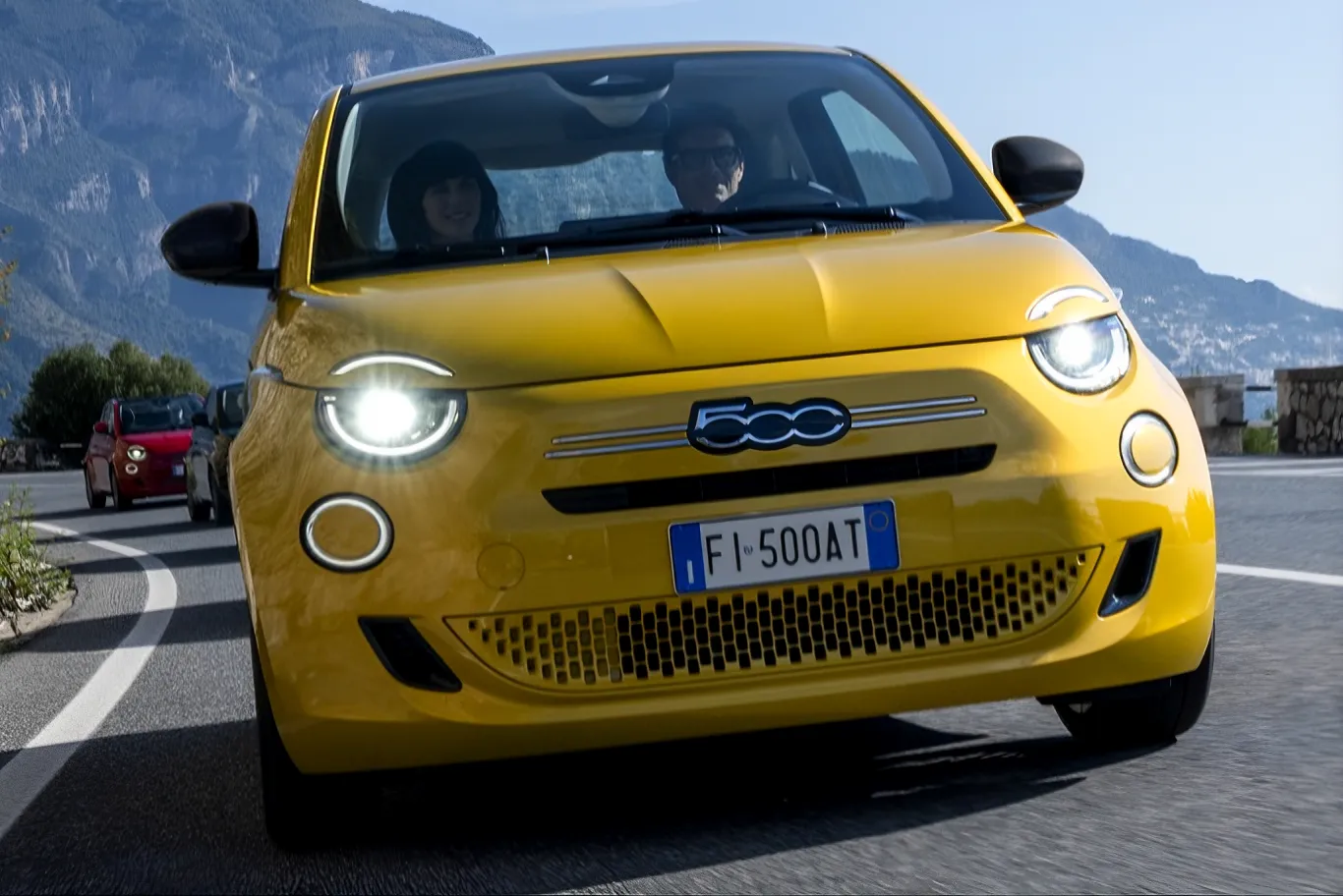 FIAT 500 ibrida di colore giallo che percorre strada ripresa di muso