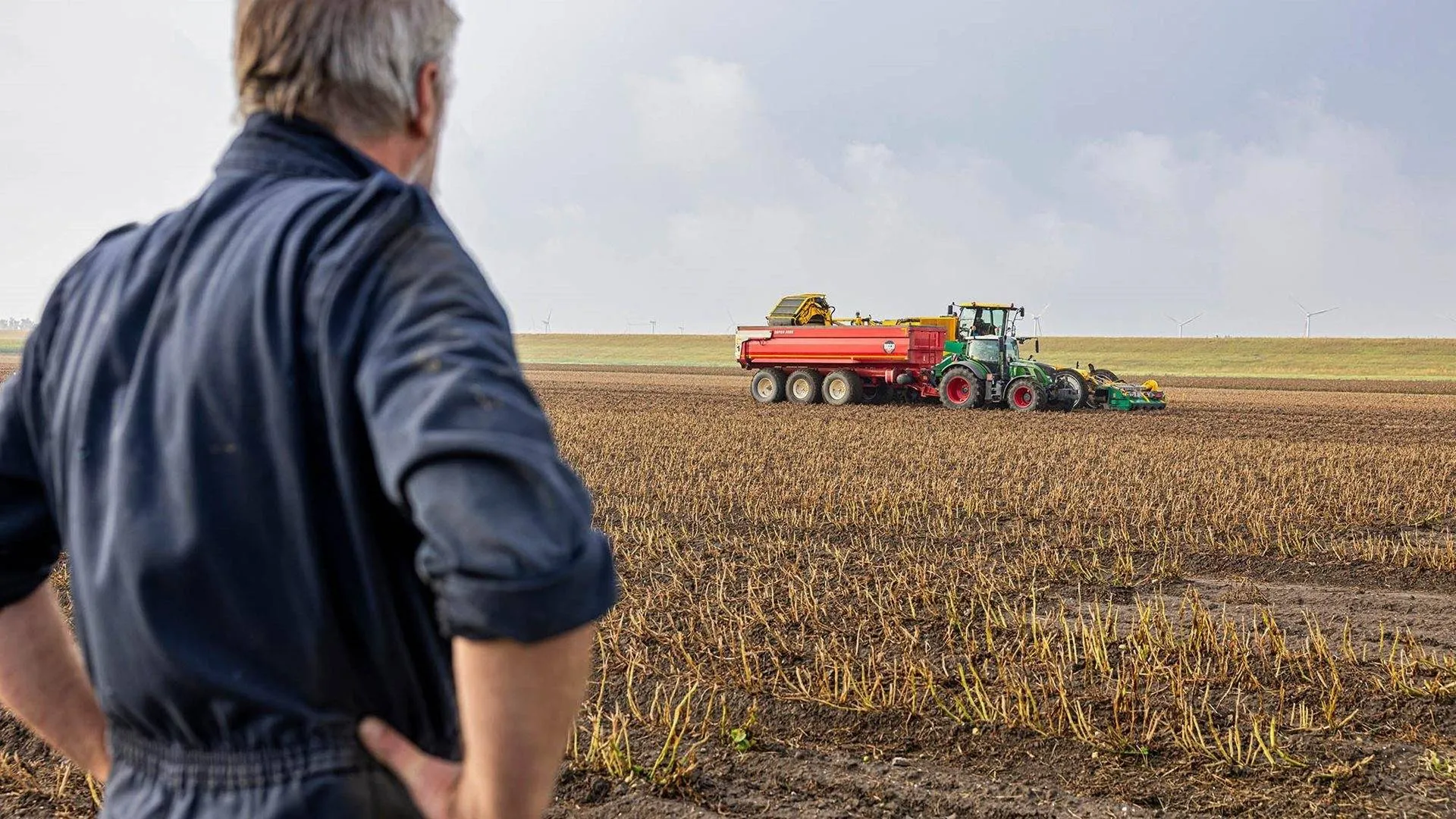 boer kijkt naar landbouwmachine prov flevoland
