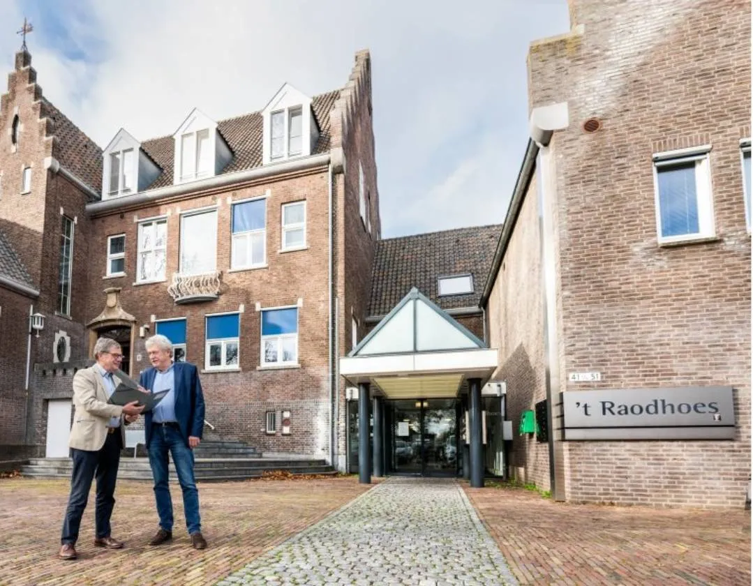 Wethouder Pustjens en wethouder Meuwissen bij het voormalige gemeentehuis in Susteren