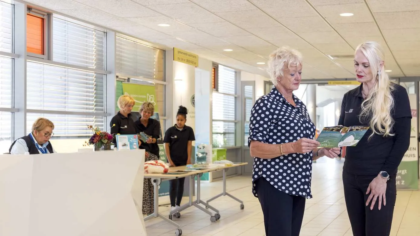 vrijwilliger sigrids garden rechts geeft informatie aan een patient