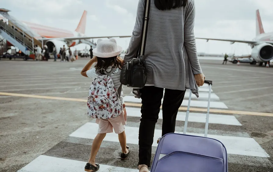 mother daughter join hands walking with suitcase23392