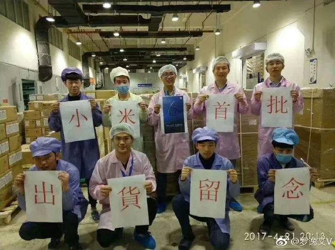 factory workers standing in front of the first batch of xiaomi mi 6 handsets getting ready to be shipped
