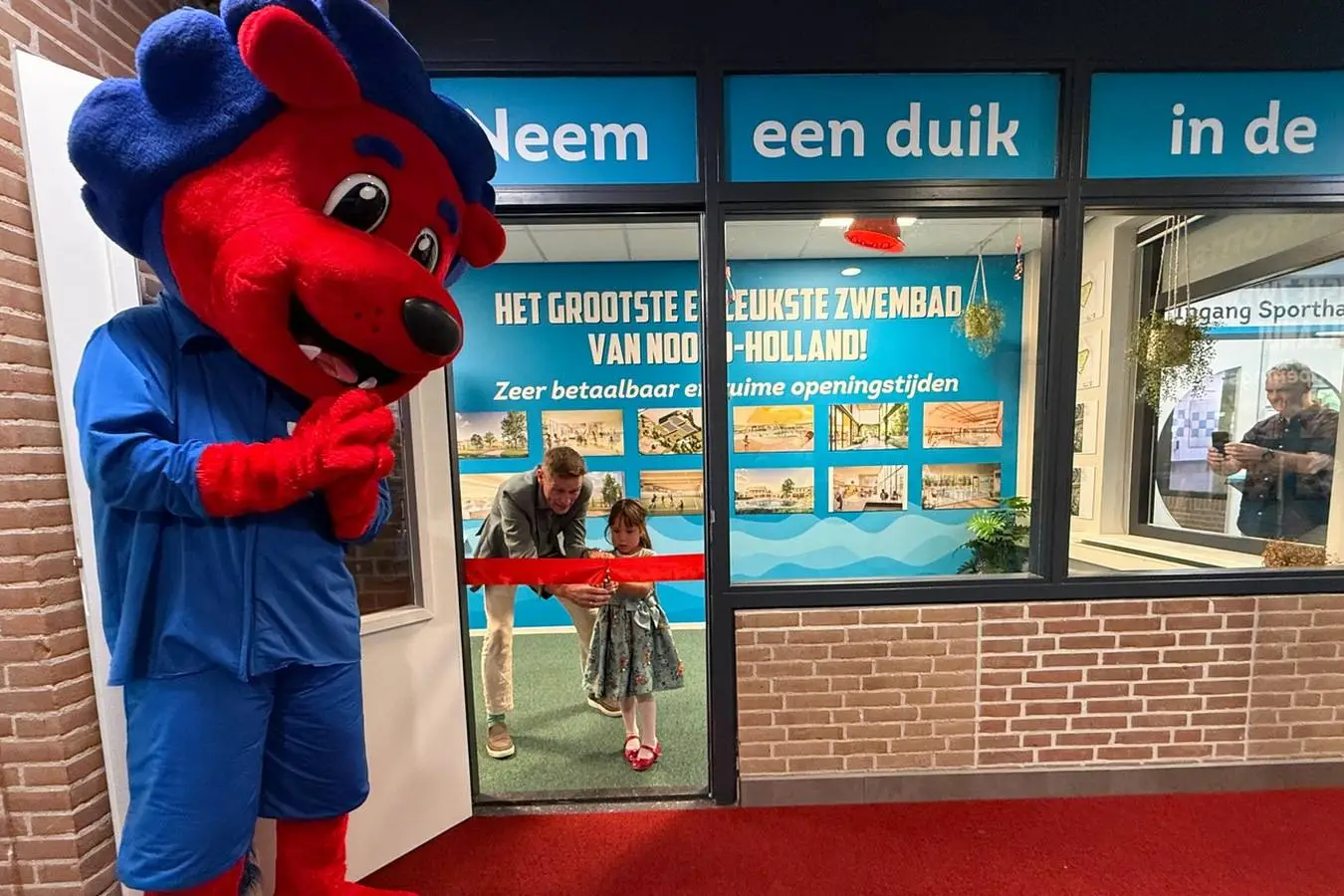 Onder toeziend oog van mascotte Freddy Fit openen Mayla Ruitenberg en Eddy Bakker samen de expositieruimte van het toekomstige zwem- en sportcomplex Hoornse Vaart 1