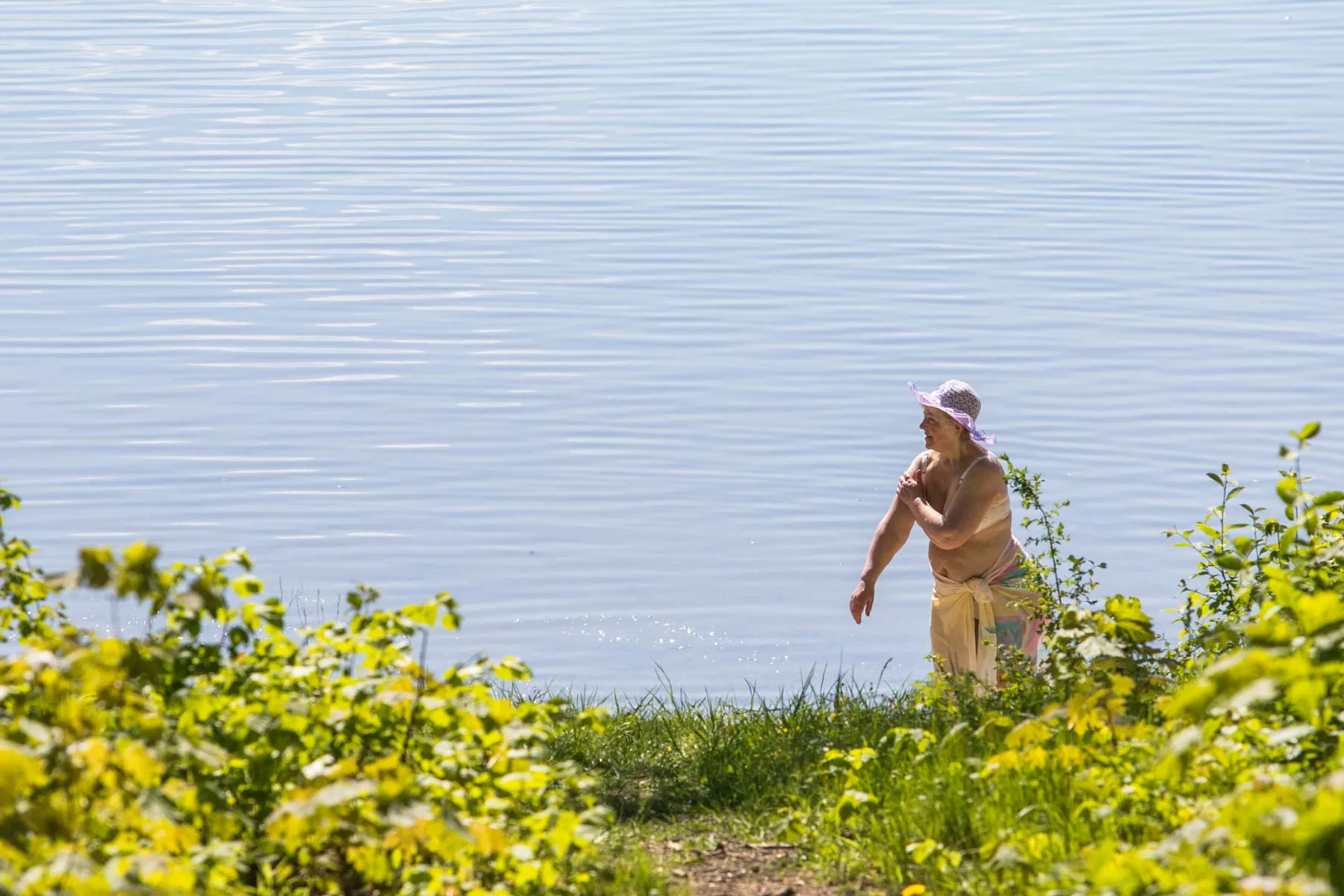 Žmonės mėgaujasi saulės šiluma prie marių
