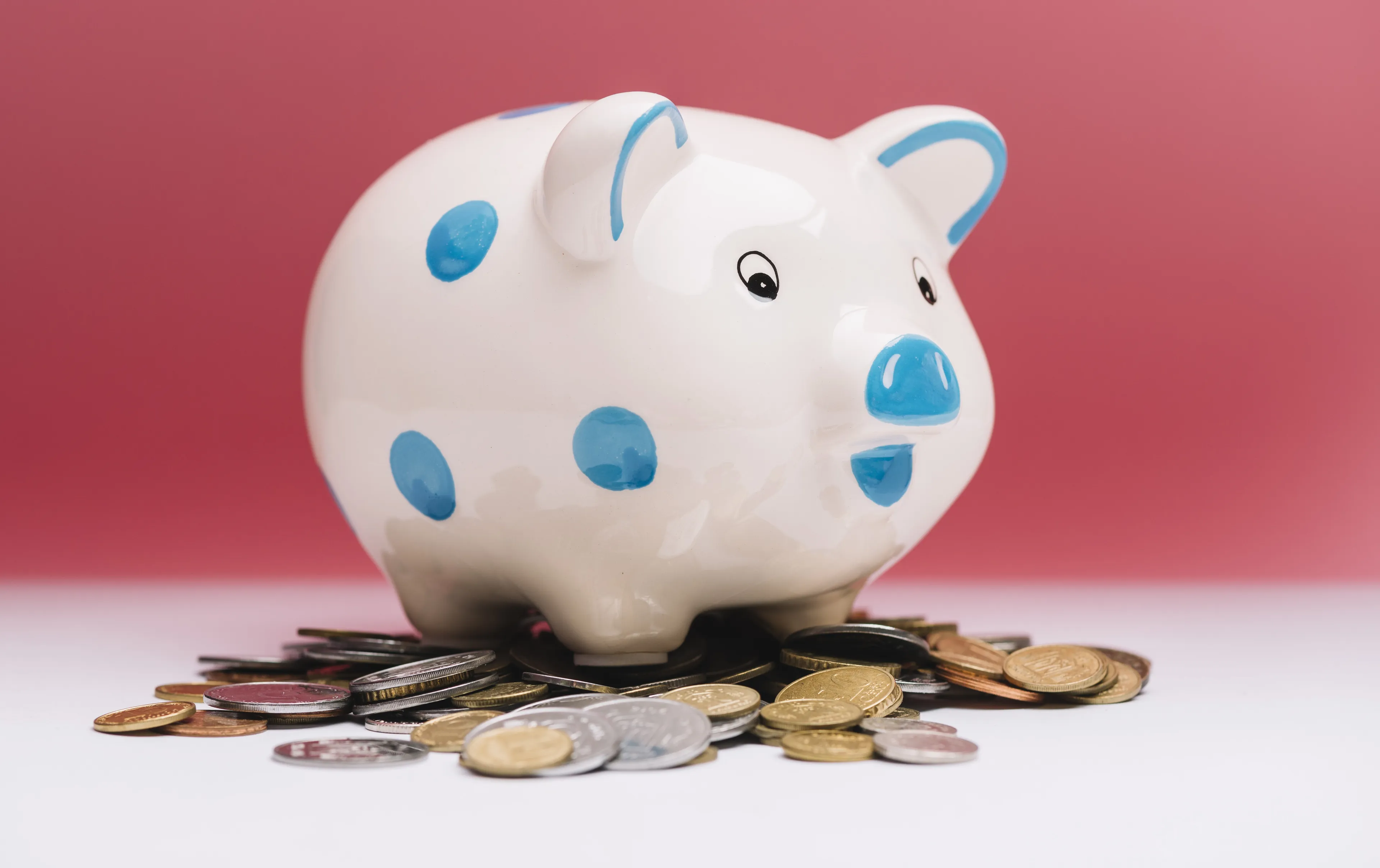 spotted ceramic piggybank coins front red background