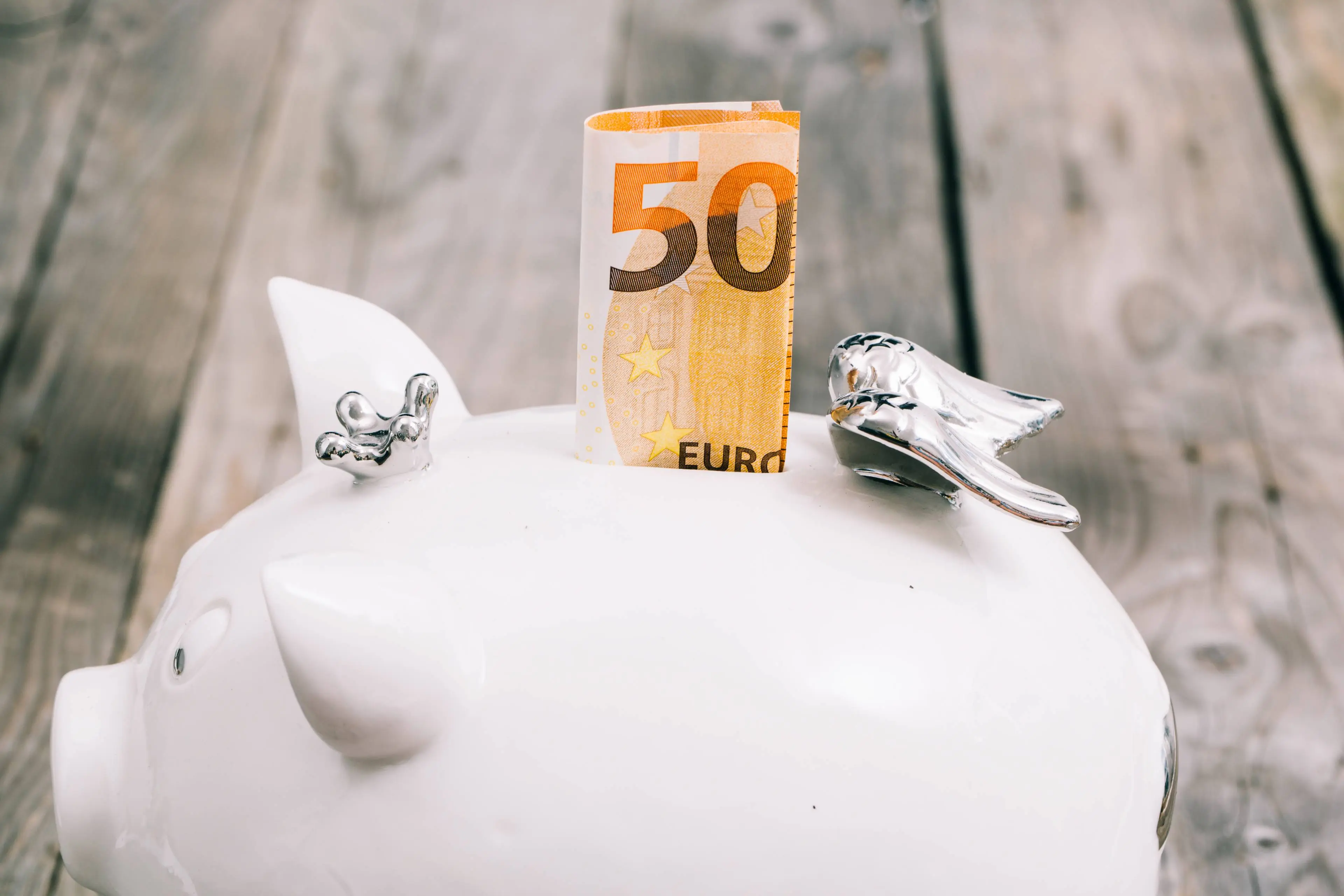 close-up-folded-fifty-euro-note-slot-white-piggybank