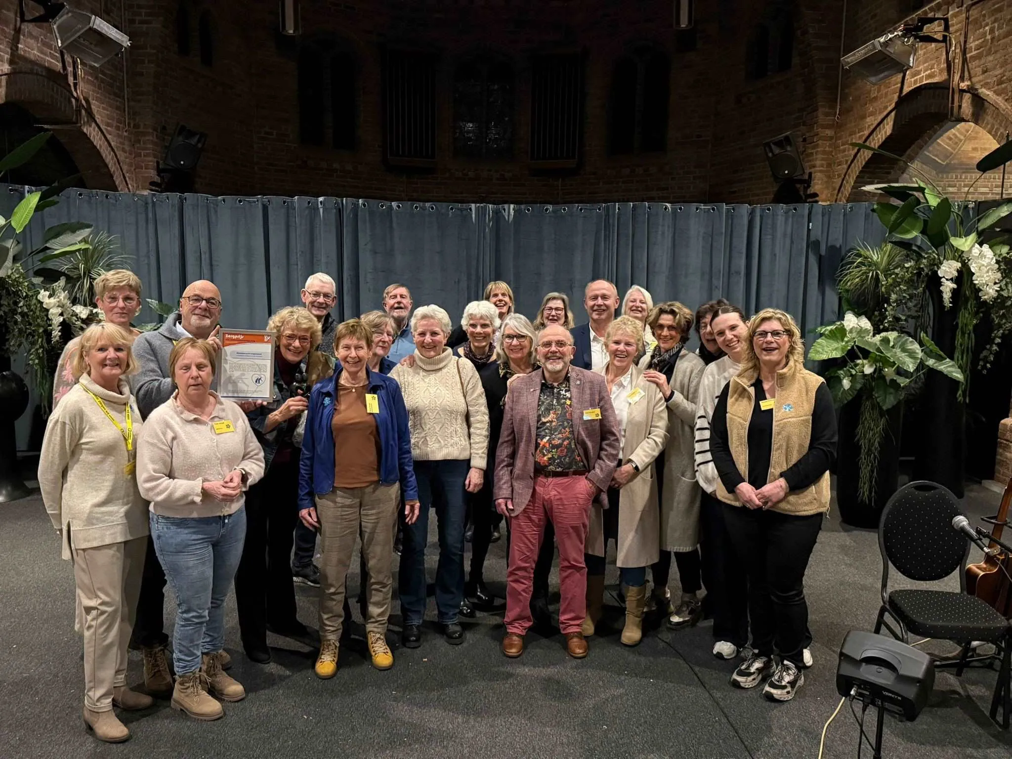Vrijwilligers Alzheimer Café Lingewaard zijn superblij met VVD-zorgprijs.Theo Aaldering overhandigde het bijbehorende beeldje twee mensen die elkaar aankijken met een hart ertussen