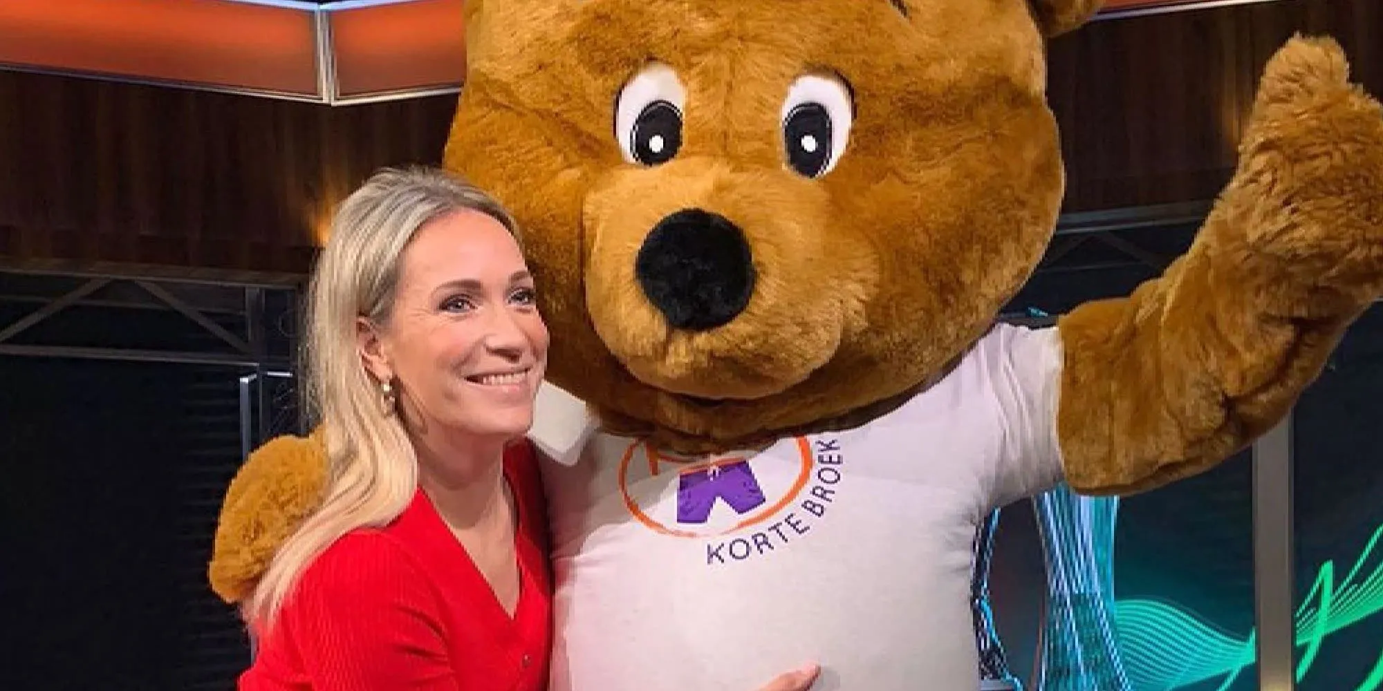helene hendriks laat zich achter de schermen innig omhelzen in rood jurkje