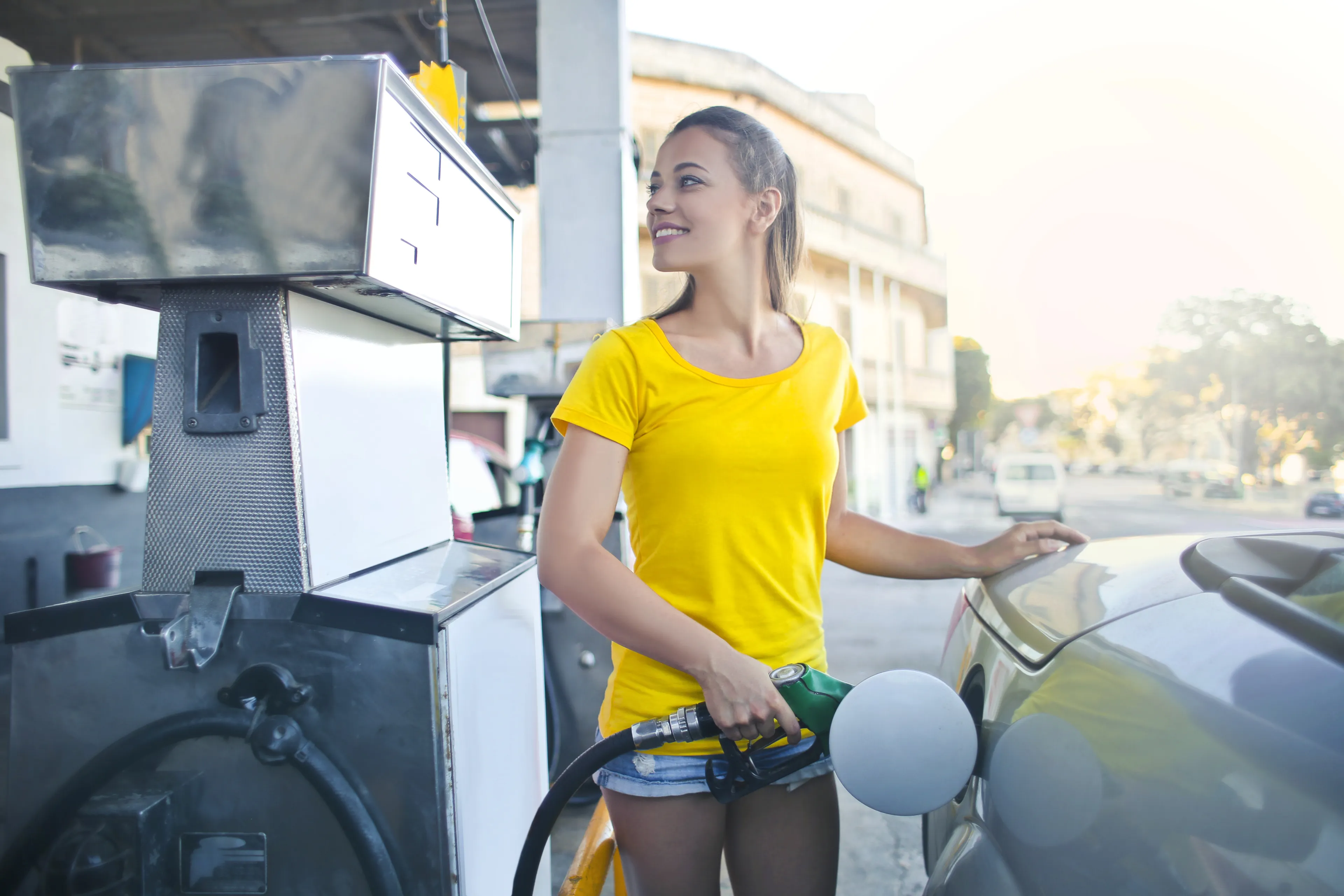 woman in yellow shirt while filling up her car with gasoline pexels