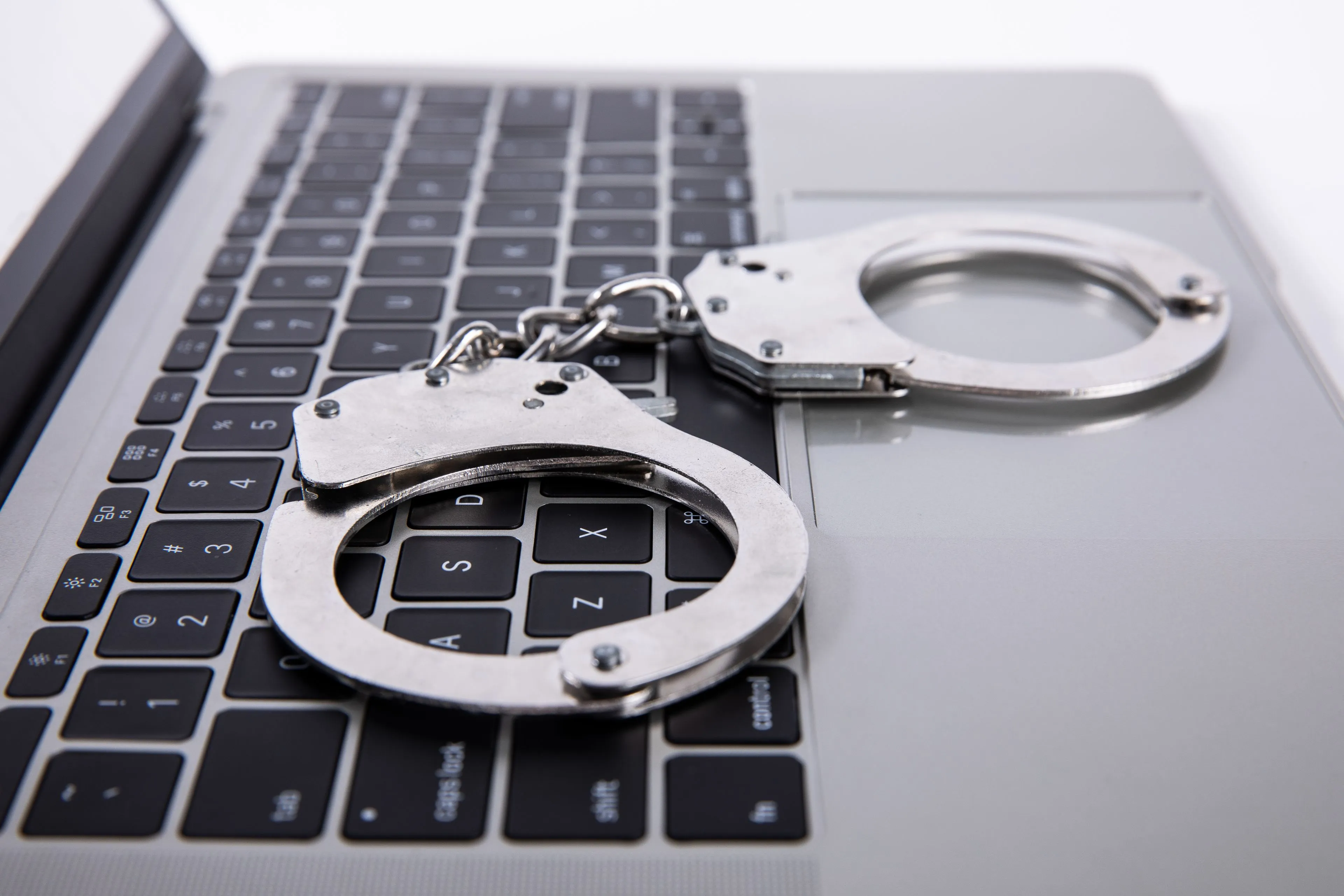 closeup shot of handcuffs lying on laptop keypad 2023 11 27 04 49 35 utc