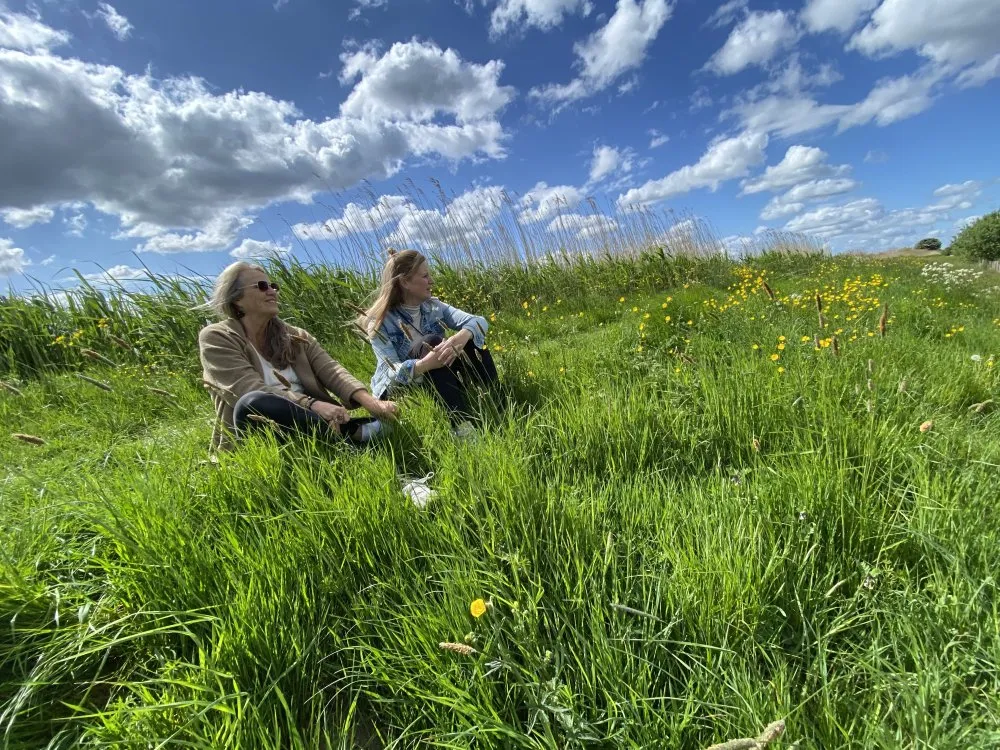 twee20vrouwen20zitten20in20het20gras20 20istock 2215005313