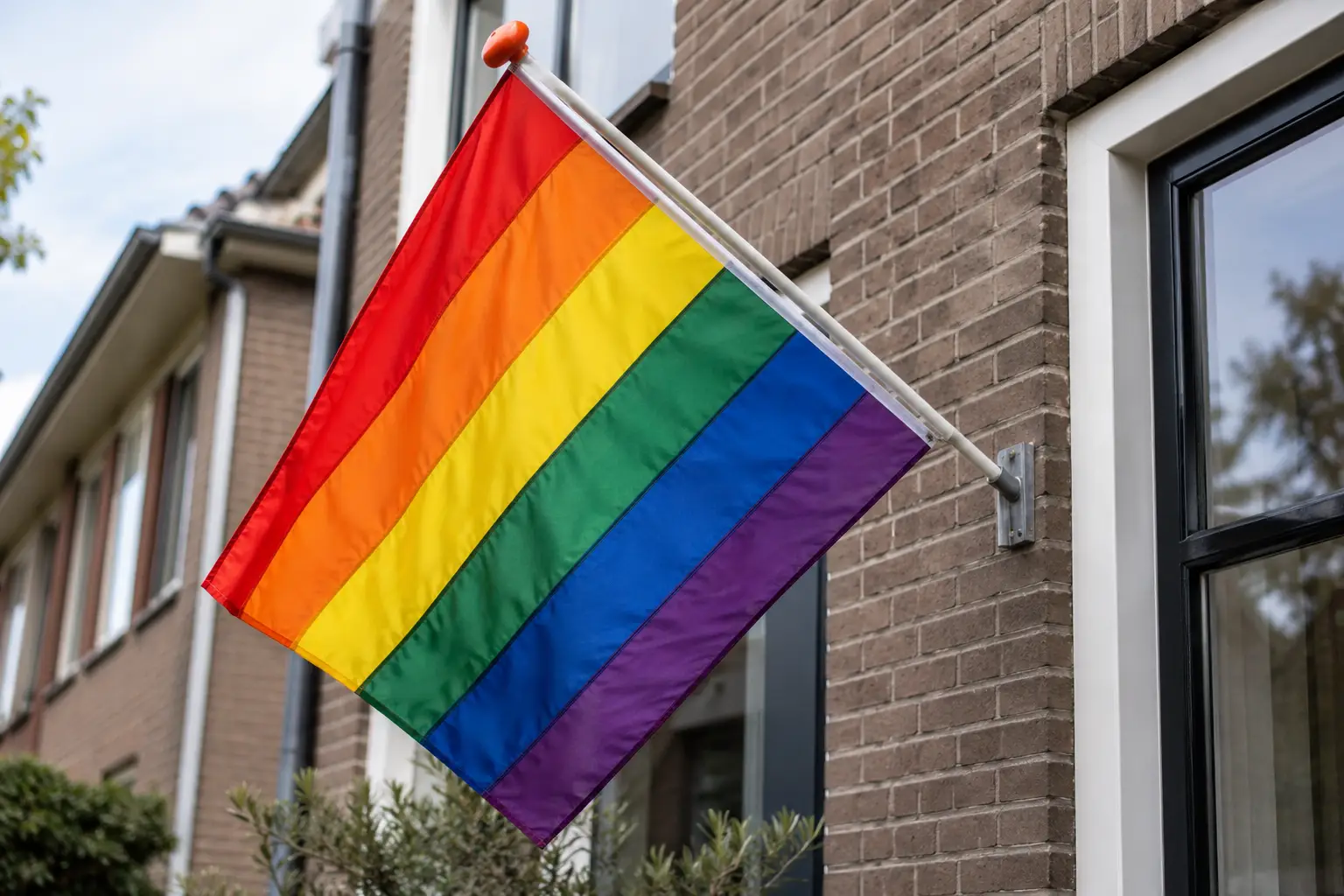 Een intacte regenboogvlag aan een woning; AI-gegenereerde illustratie