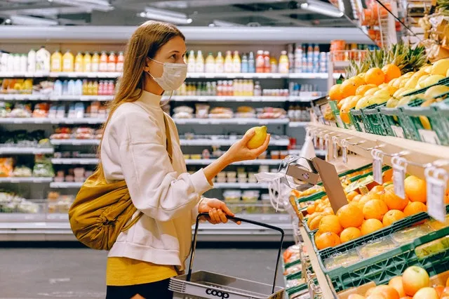woman in yellow tshirt and beige jacket holding a fruit 3962285