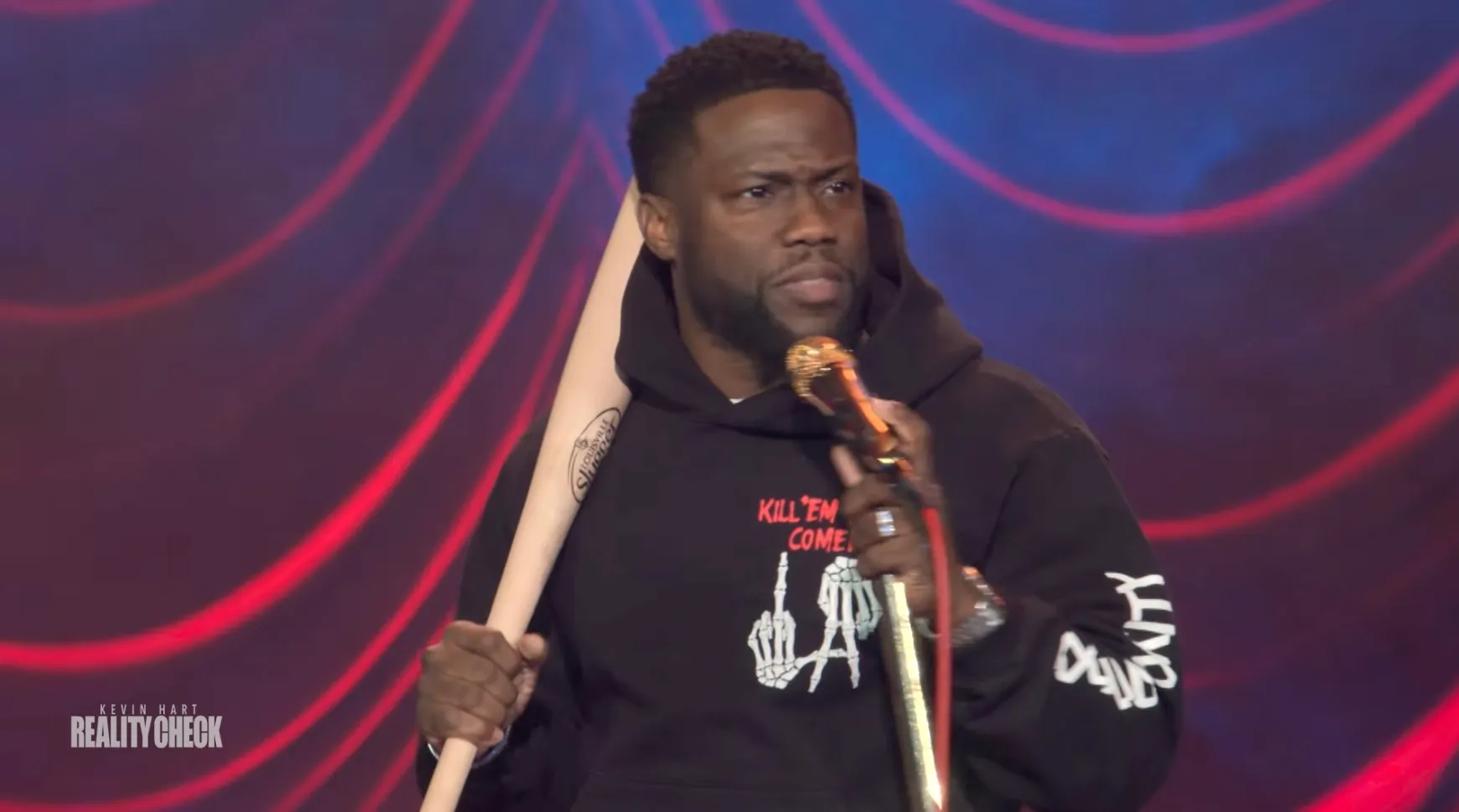Kevin Hart neemt een knuppel mee het podium op om zich te beschermen in
