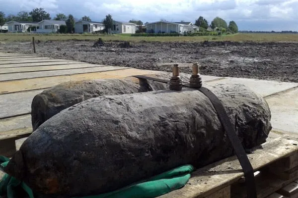 de zojuist gedemonteerde vliegtuigbommen met op de achtergrond de vakantiewoningen die moesten worden ontruimd