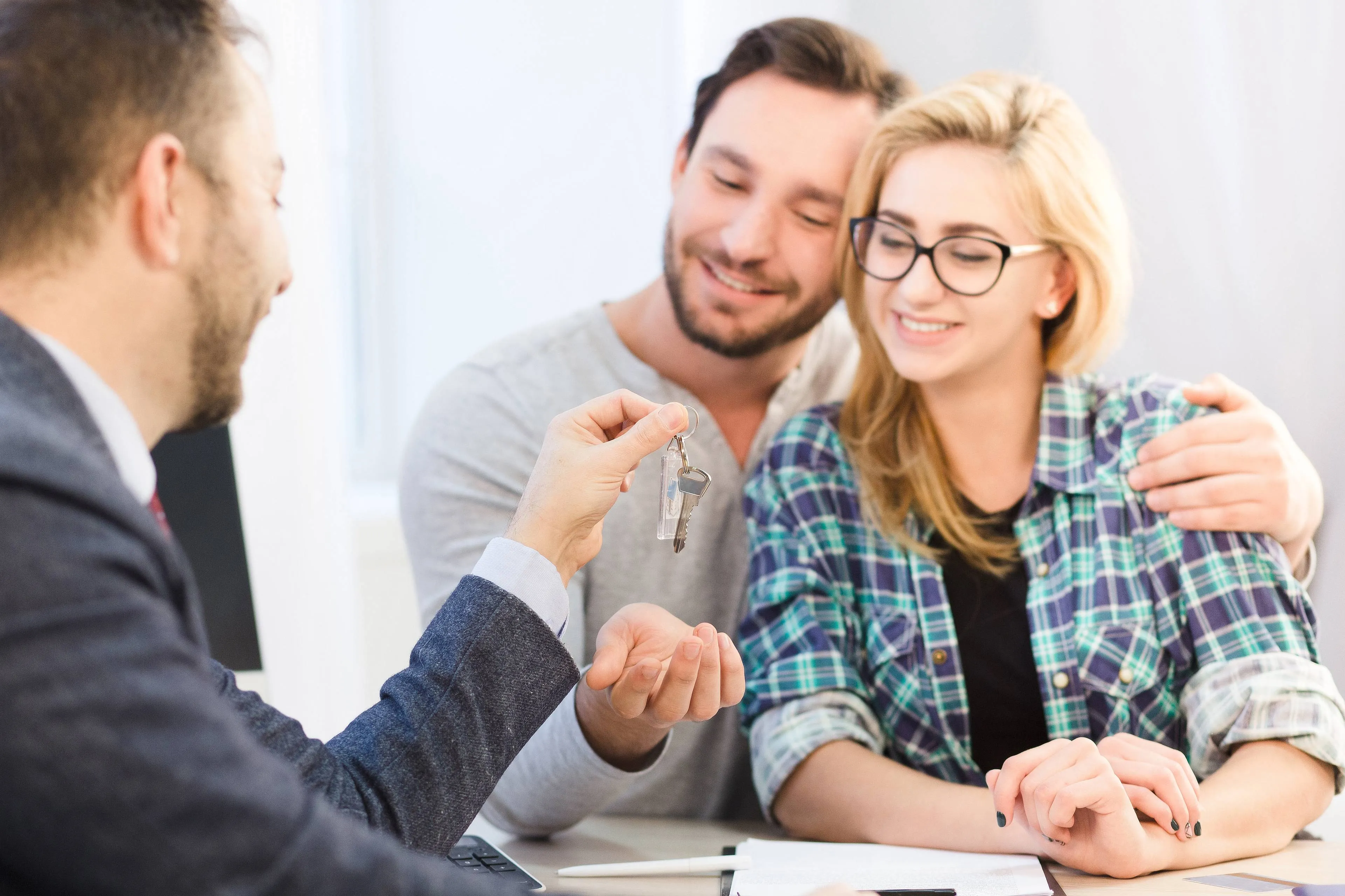 dealership-concept-bank-concept-toned-sales-manager-ready-give-key-young-couple-love-after-signing-agreement-contract-purchase-sale