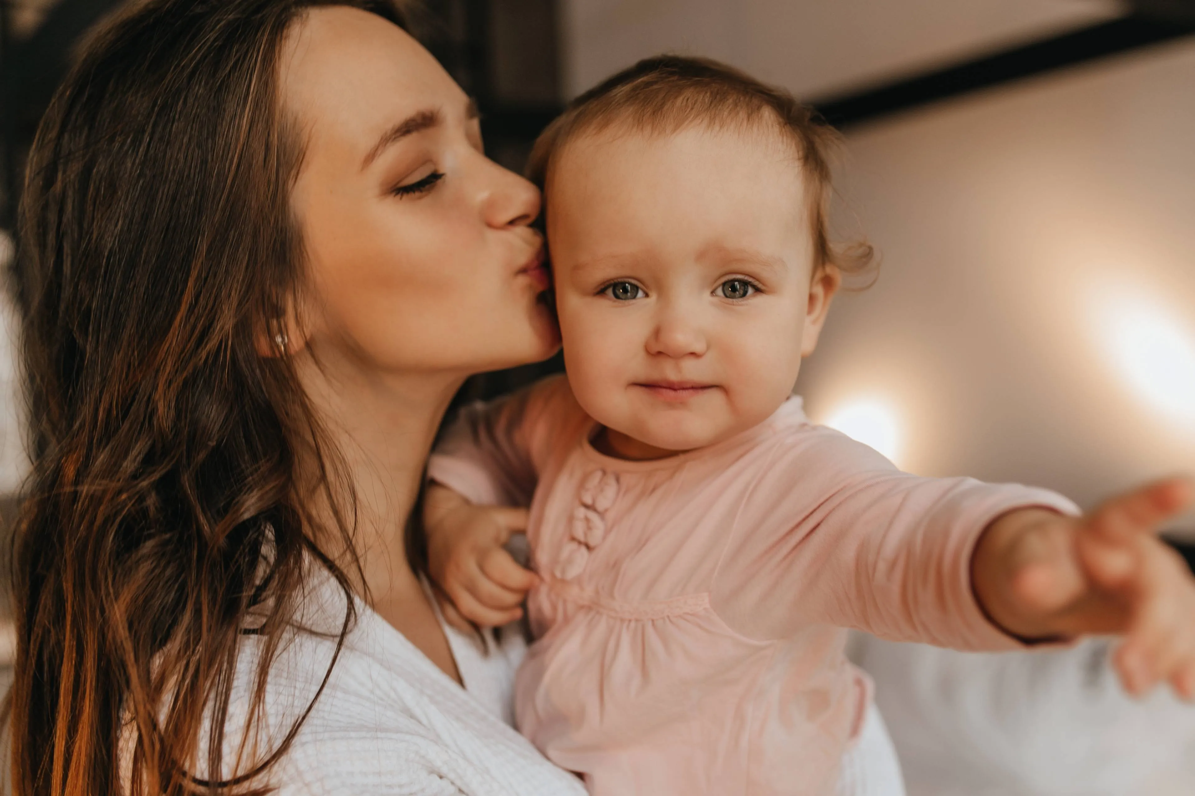 portrait-woman-white-home-clothes-her-blue-eyed-baby-lady-lovingly-kisses-her-daughter