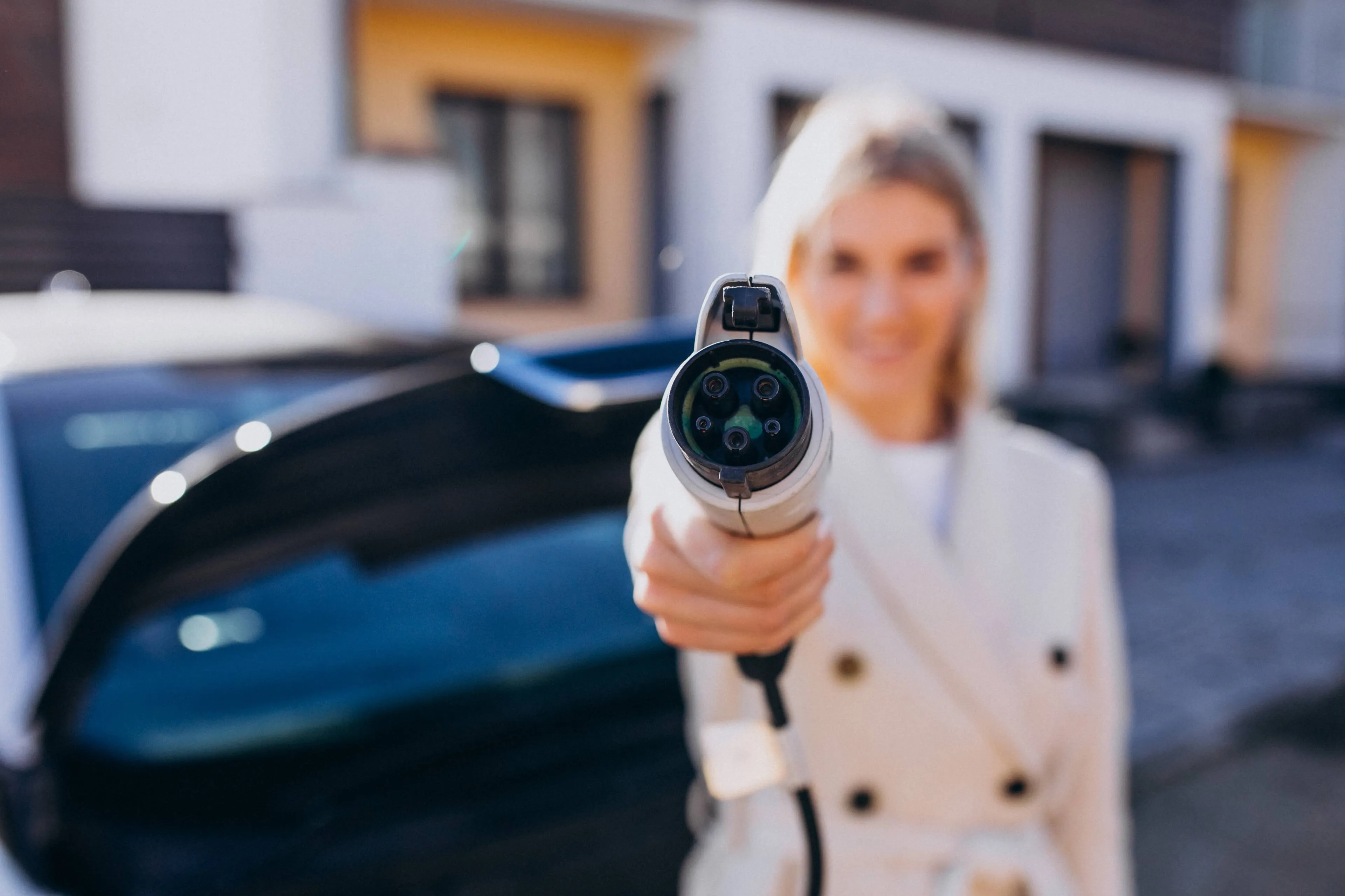 woman-charging-electro-car-by-her-house-holding-charger