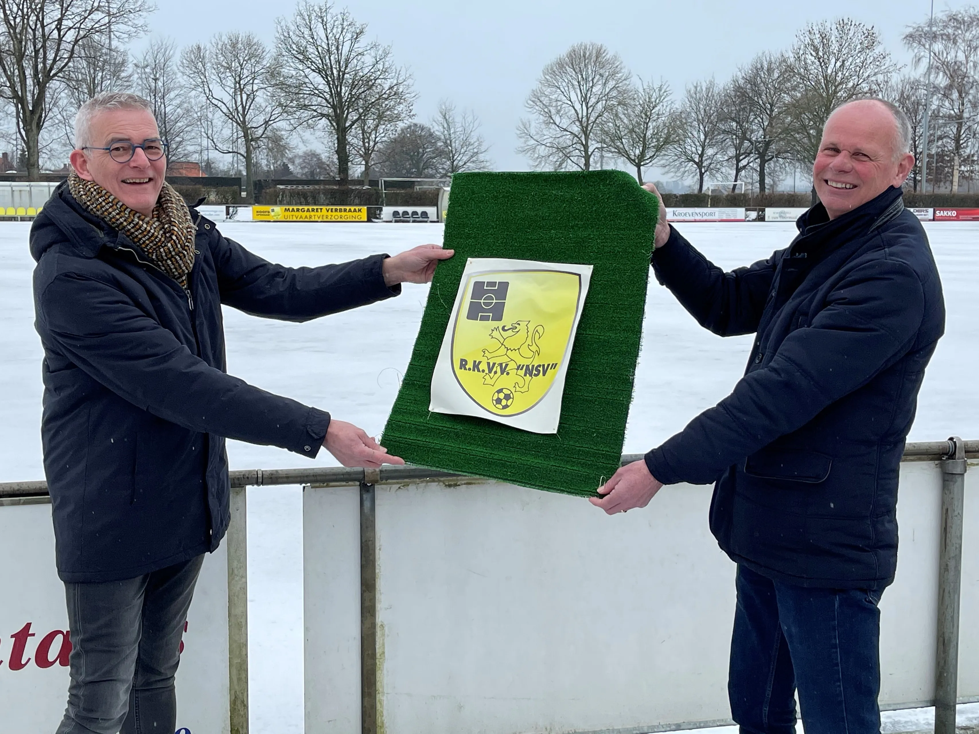wethouder rene van ginderen links geeft nsv voorzitter jan gommers alvast een symbolisch stukje kunstgras 1