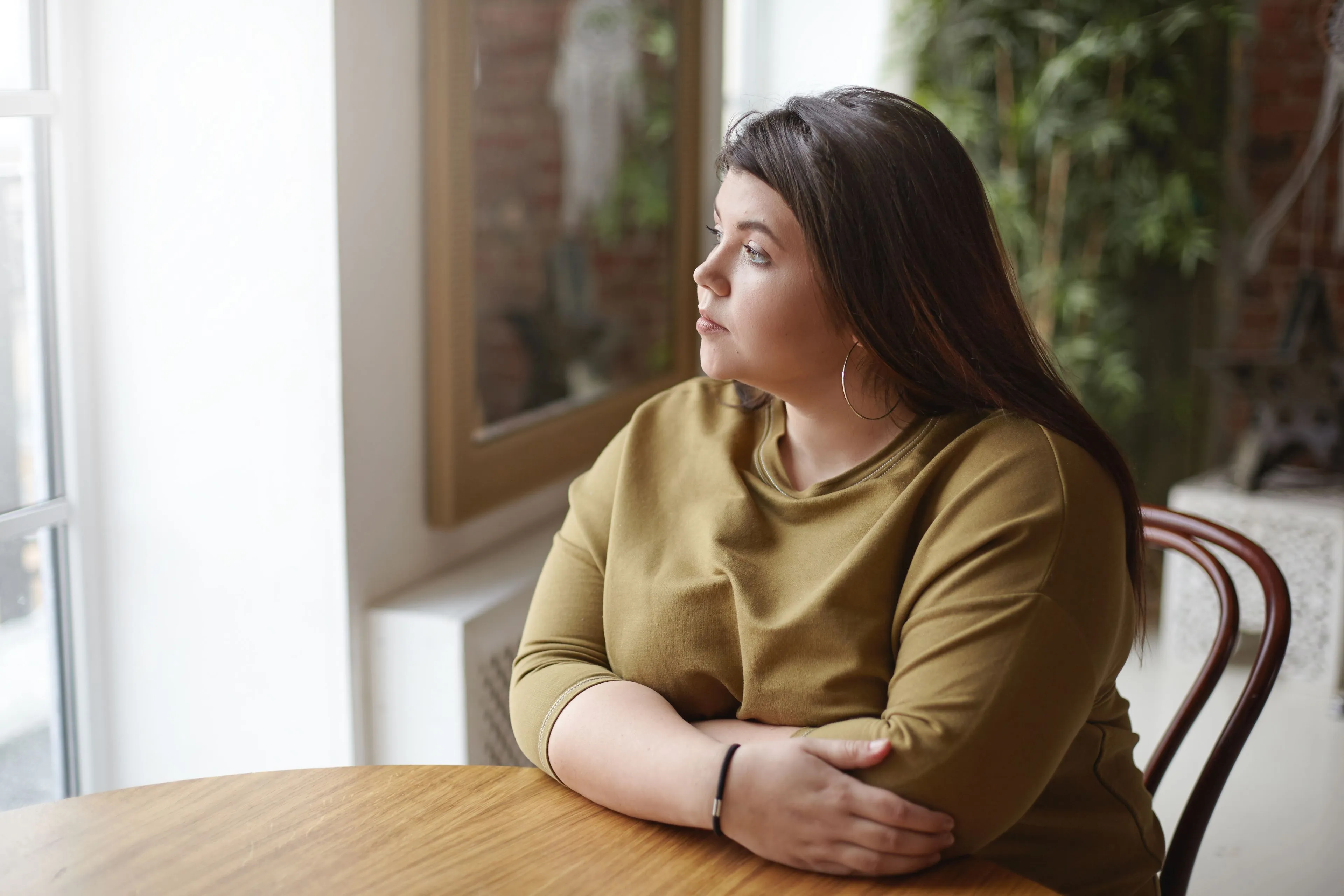 loneliness concept young brunette plus size woman with black hair sitting cafe table feeling lonely spending time alone waiting her lunch looking through window with sad pensive expression