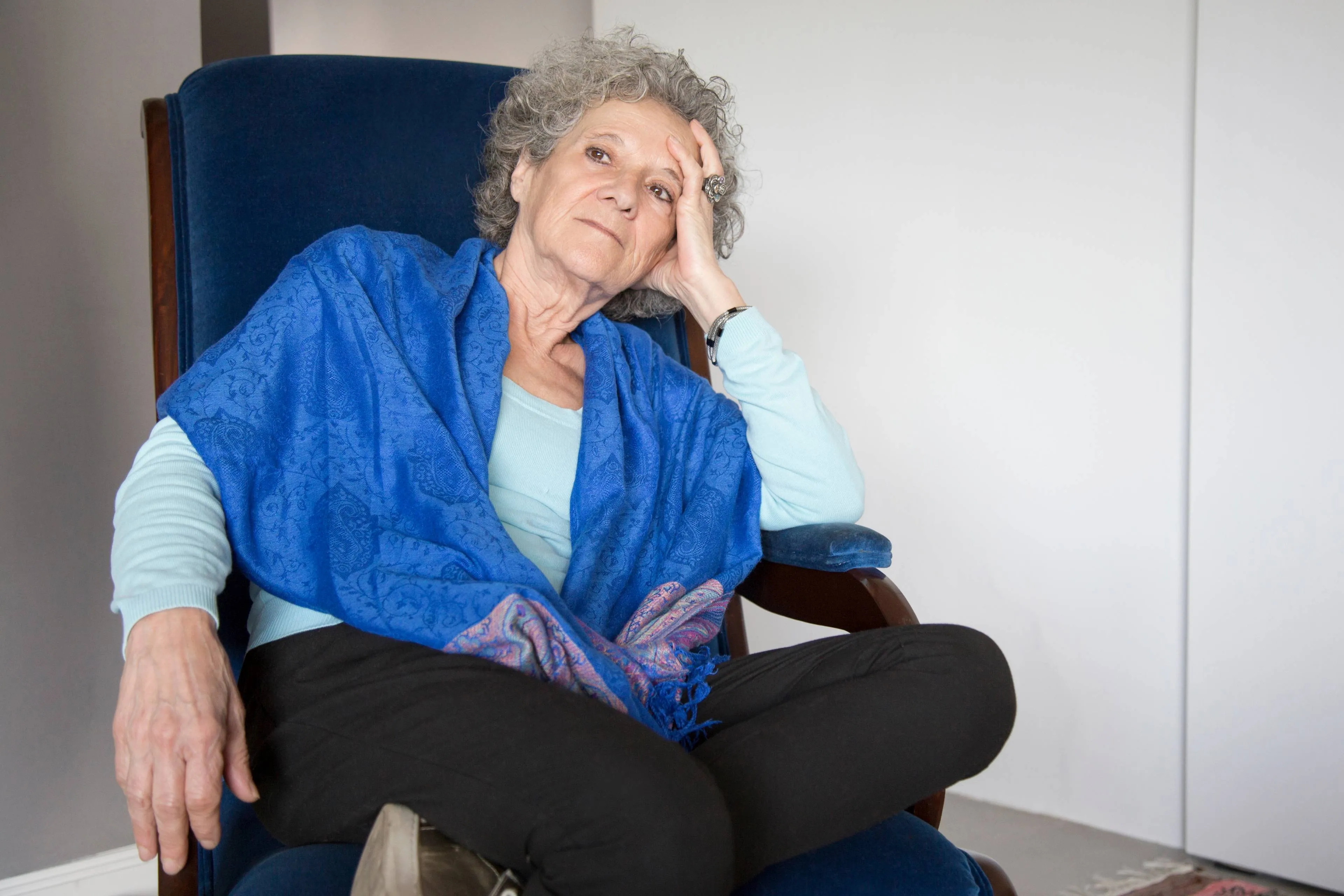 pensive senior lady sitting rocking chair looking away